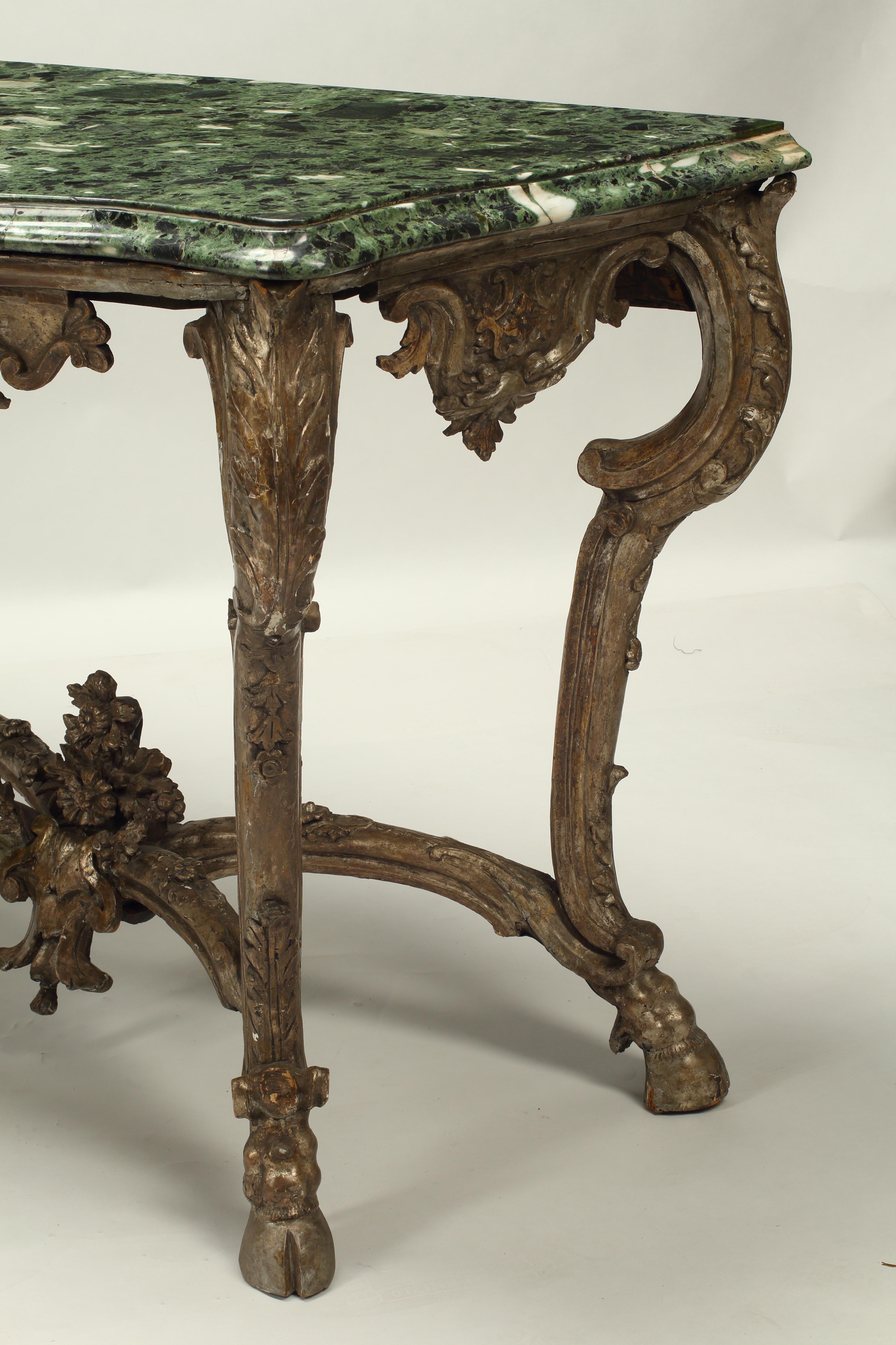 Questa bella coppia di consolle con finitura Borghese del XIX secolo è un esempio di arte classica italiana. Ogni console è sormontata da un ricco marmo serpentino che sovrasta un fregio intagliato a cartiglio. Le gambe a cabriola, graziosamente