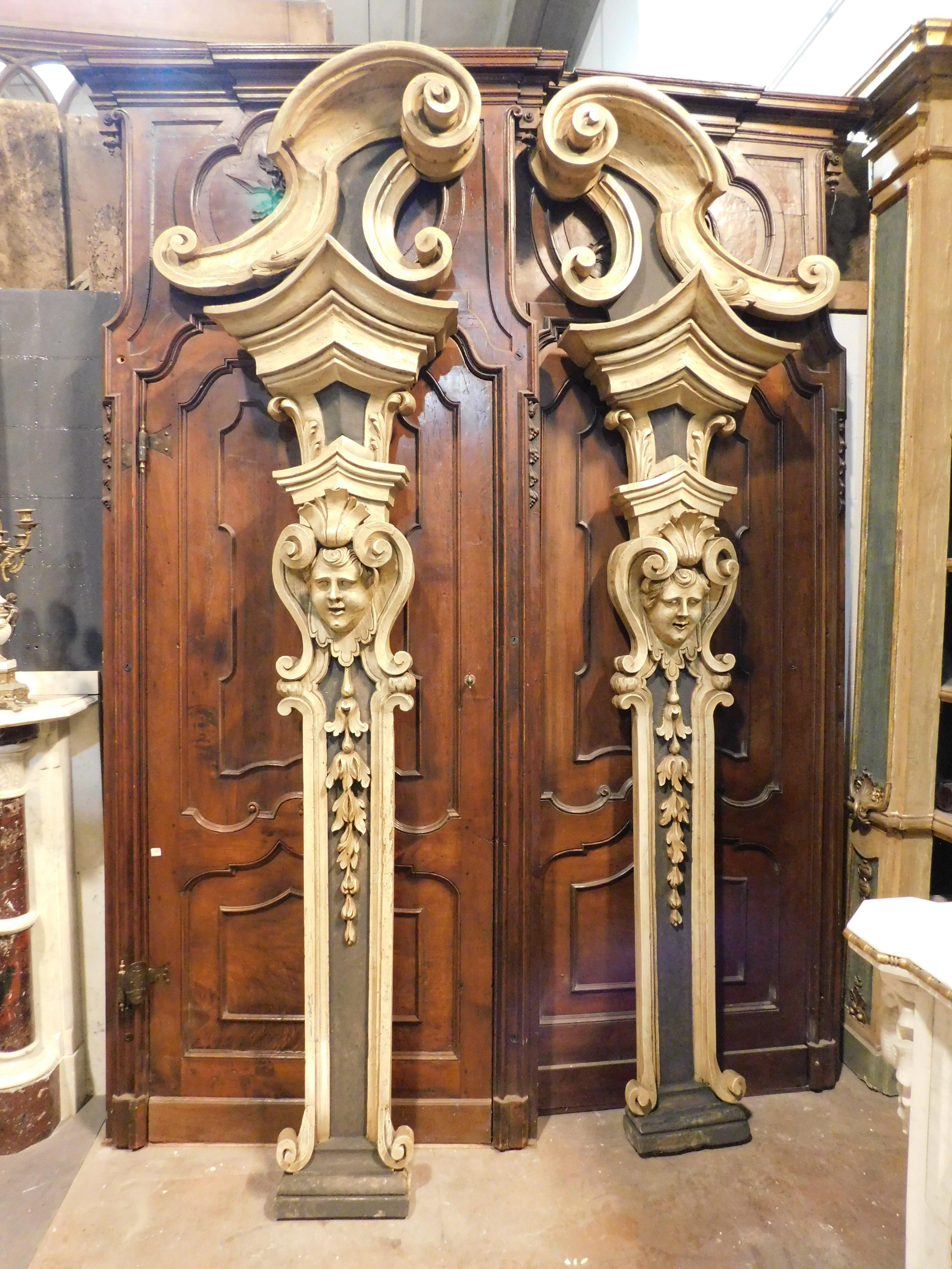 Ancient antique pair of pilasters, hand-carved support columns, richly carved with period decorations and faces of children, hand lacquered in shades of forest green and dark beige, probably coming from a rich noble house or church, from Italy,