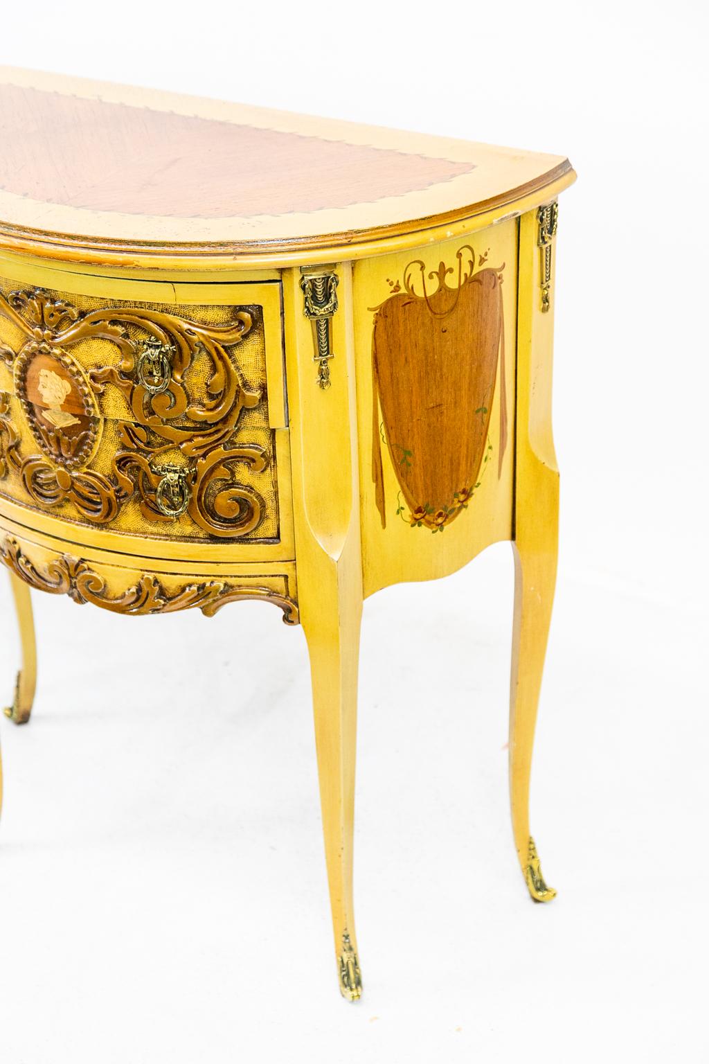 Pair of carved demilune side tables are American made in the French style. There are carved leaf arabesques on the front and book matched walnut herringbone pattern on the tops. Cast brass ornamentation is at the top and feet of all four legs.
 