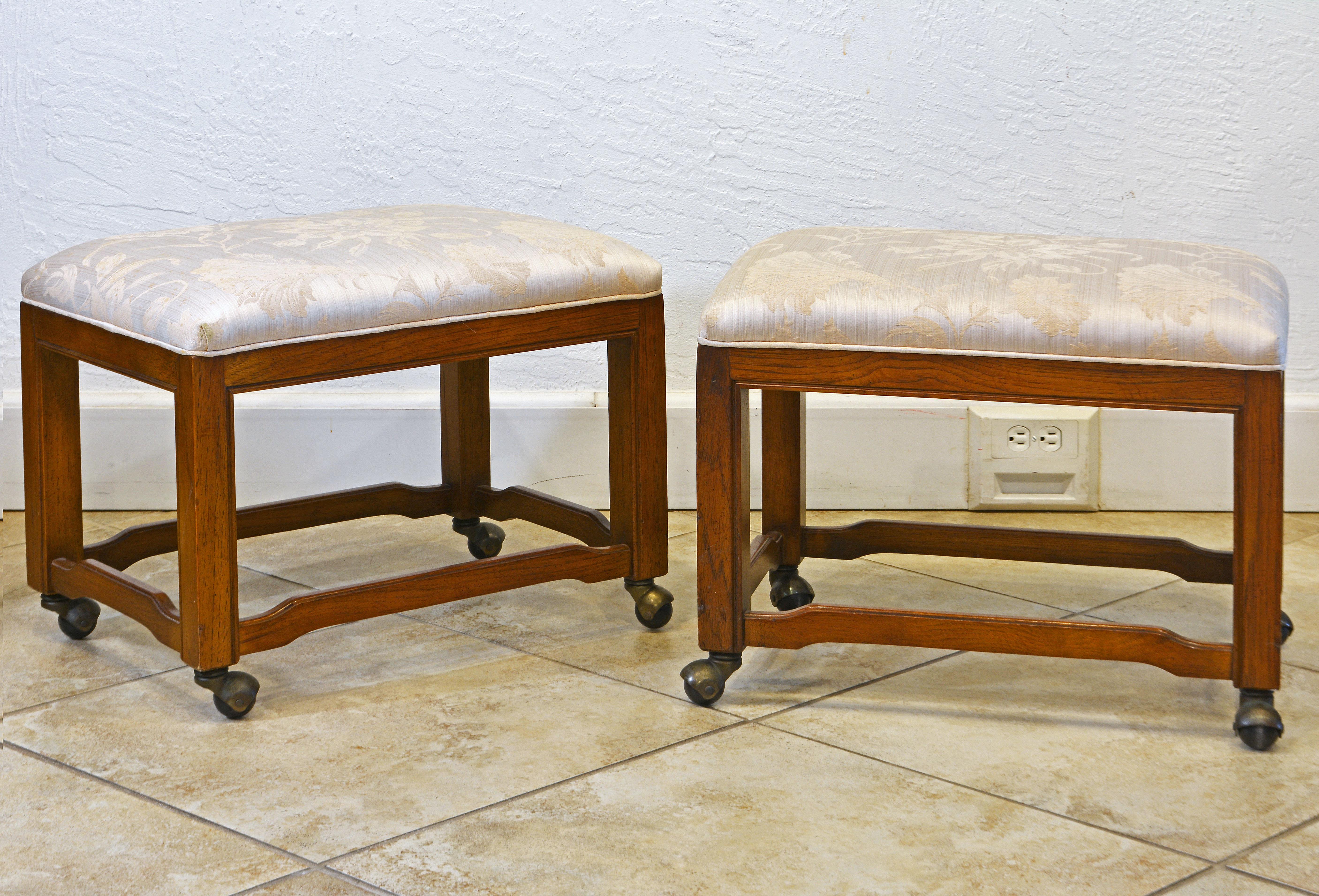 These upholstered benches by Drexel Heritage arevery useful because of the well functioning wheels. The are designed in the mid century style with a chinoiserie twist. The walnut frames are sturdy and well detailed. The seats are covered by a damask
