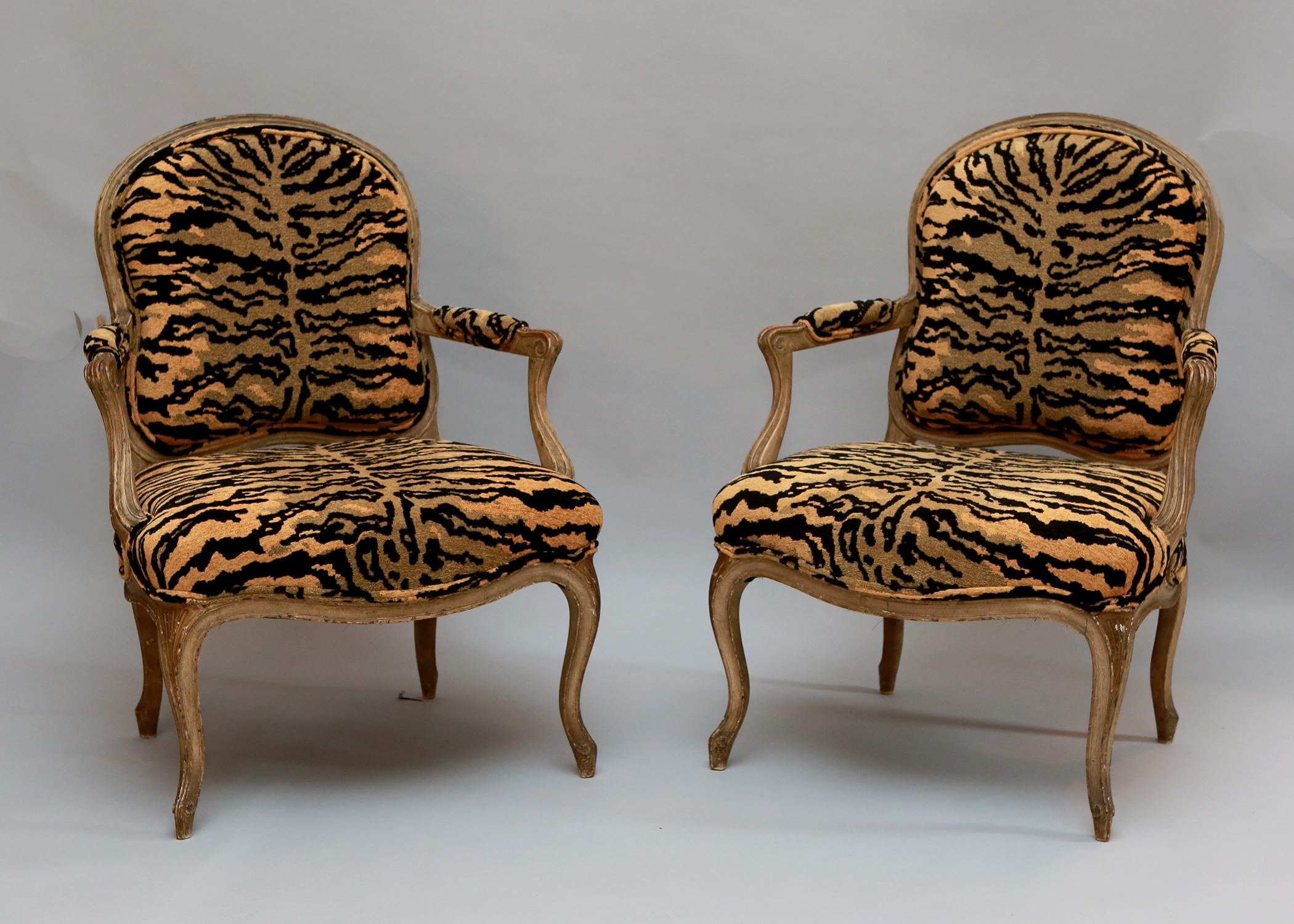 Pair of French carved armchairs with animal print upholstery, gracefully curved legs, and ample seat. Frames are natural wood. 40 1/2