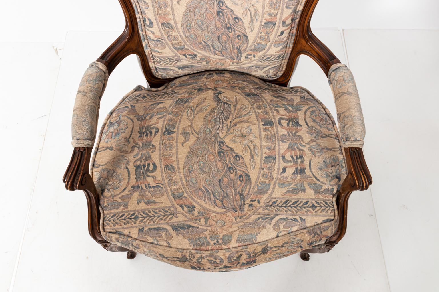 Pair of French Rococo style carved wood armchairs with peacock upholstery, circa 1970s. The piece also features carved floral details and cabriole legs. Made in the United States. Please note of wear consistent with age including chips and finish