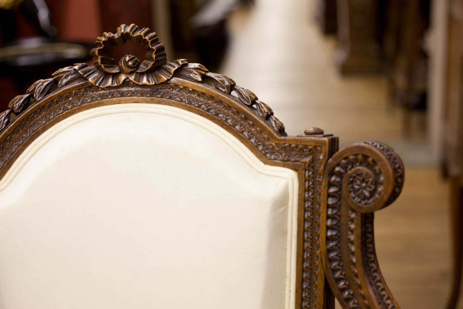 Pair of carved French walnut upholstered armchairs, with bell flower and ribbon carving on crest, spiral turned legs.


           