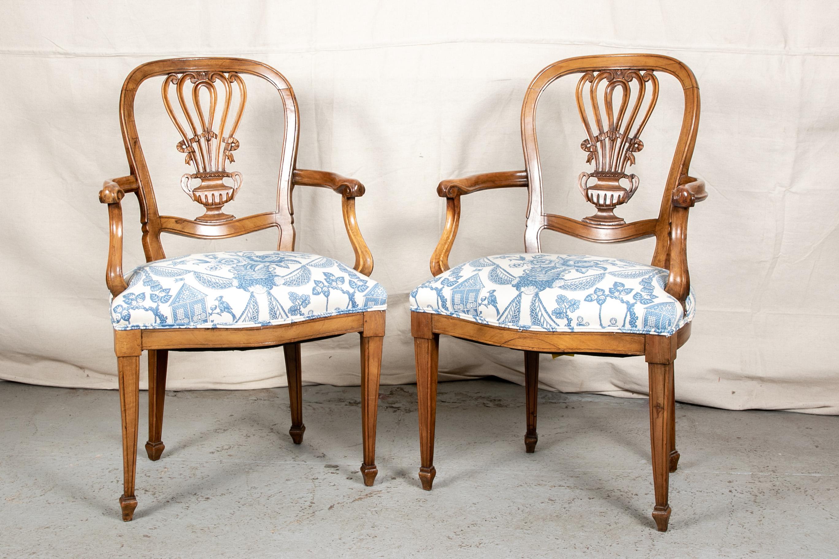 Pair of carved fruitwood armchairs, elaborate openwork scrolled floral urn splats with ribbon details. Curved arms with scrolled ends, raised on square tapering legs with spade feet. The shaped seats upholstered in a blue and white print.