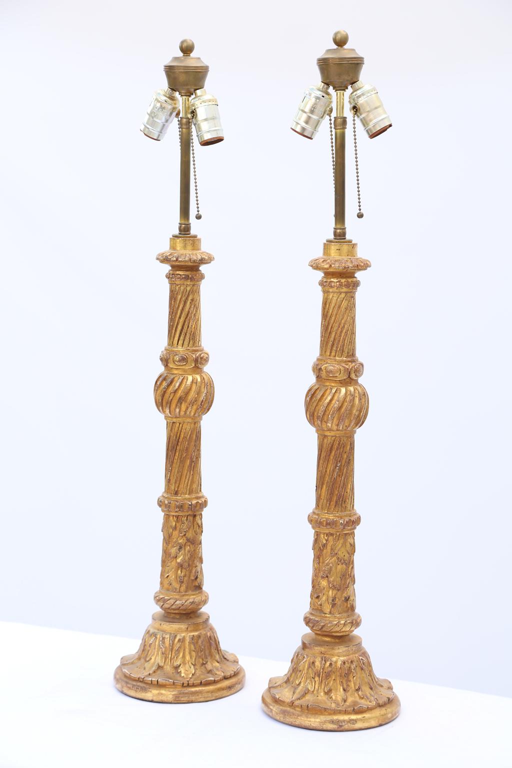 Pair of lamps, of giltwood, each a tall candlestick form, hand carved with raised spiral reeding, acanthus, and beading, raised on round footed base. 

Stock ID: D1998.