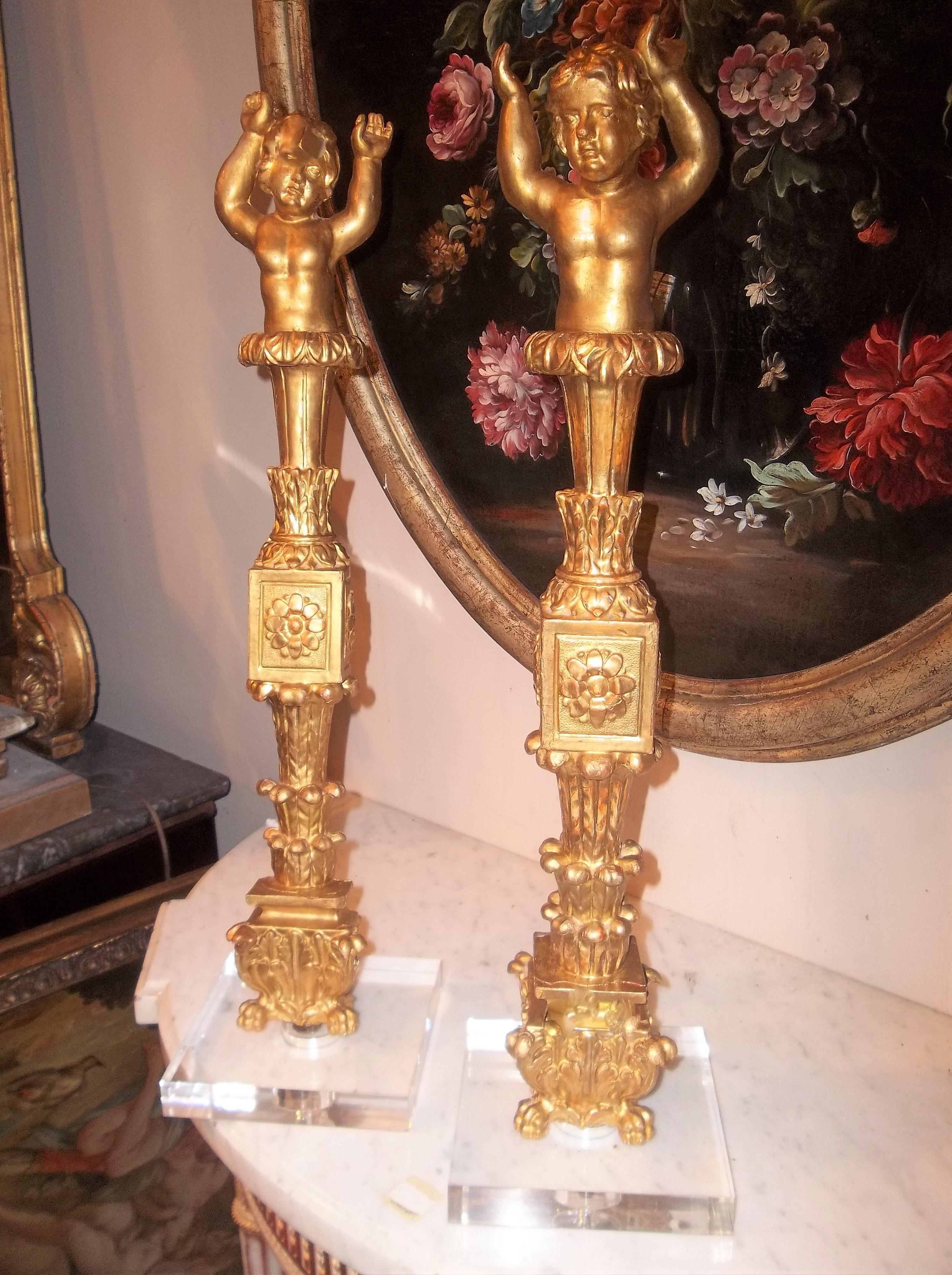 On acrylic bases (6 inch square). Gilt and water gilt, cherubs on top of neoclassical stylized columns. 

Either cut off a cabinet or boiserie (panelling), the hands in upward support, flat pilaster type back. The bases pre-drilled for lamp wirings