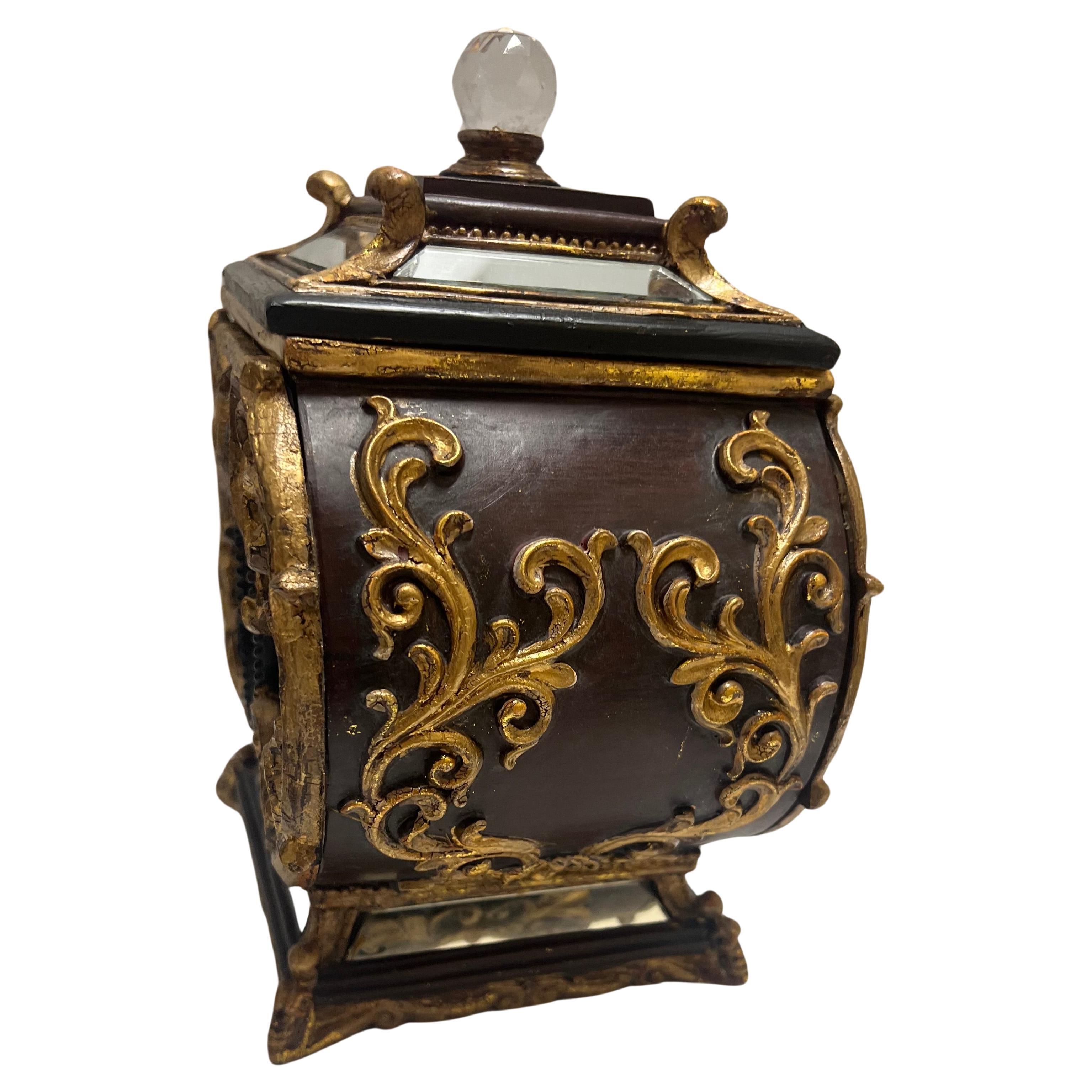 A pair of carved giltwood mirrored boxes with covers.  Carriage design body with a wood grain burgundy and black colors.  Ornate gold scroll work with acanthus leaf accent.  Mirrored panels on front and borders of base and cover.  Lids have