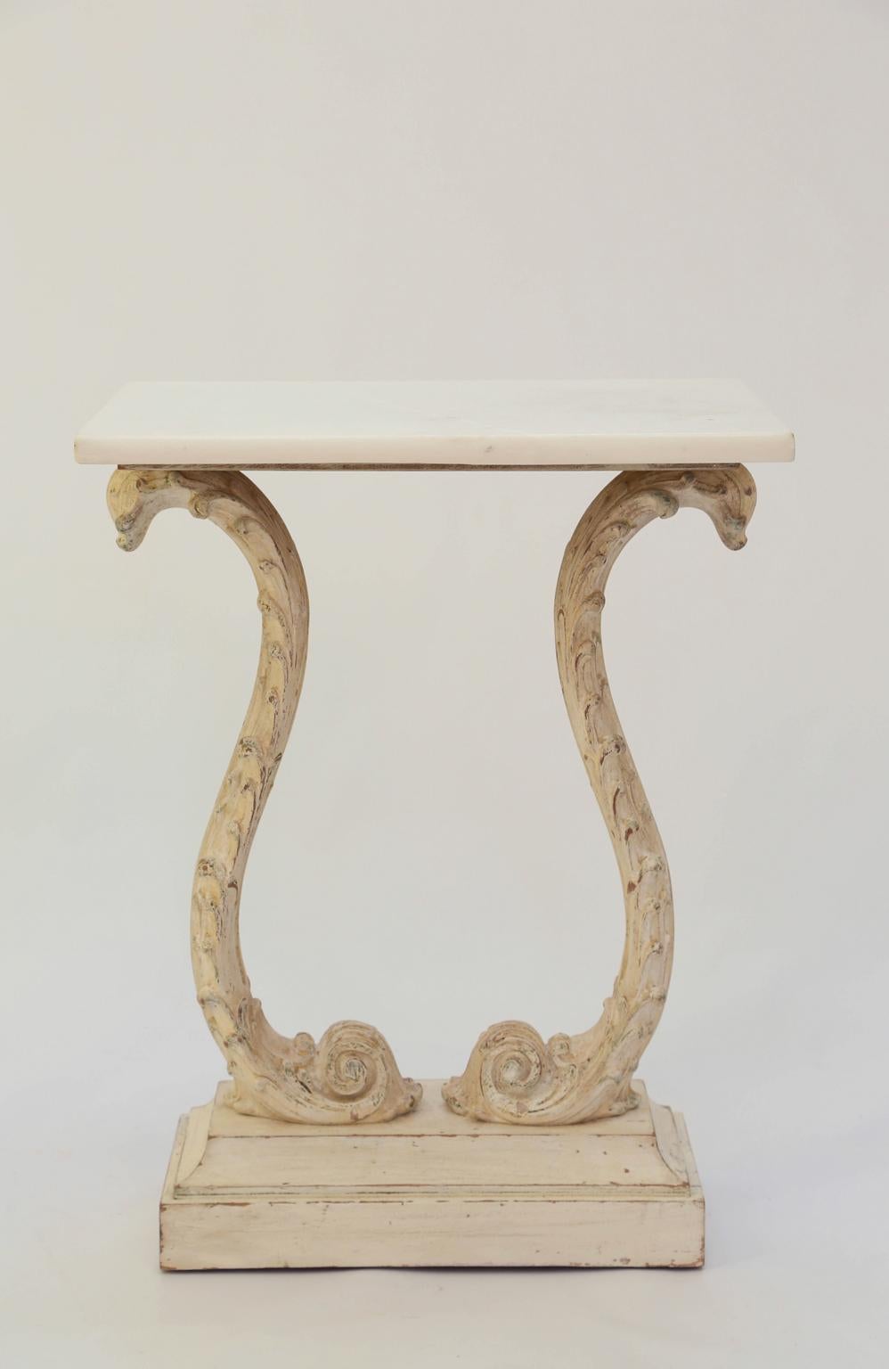 Pair of end tables, each having a rectangular top of marble, on a painted base showing natural wear; the double scrolled base carved with waves, raised on a graduated plinth.

Stock ID: D2452.