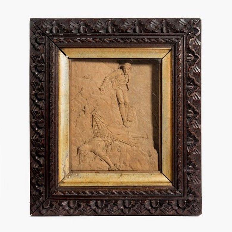 A pair of Swiss carved lime-wood pictures one showing a hunter being attacked by an eagle as he attempts to raid its nest, the other a climber rescuing a girl who has fallen while picking flowers and been saved by her clothing snagging on a branch,