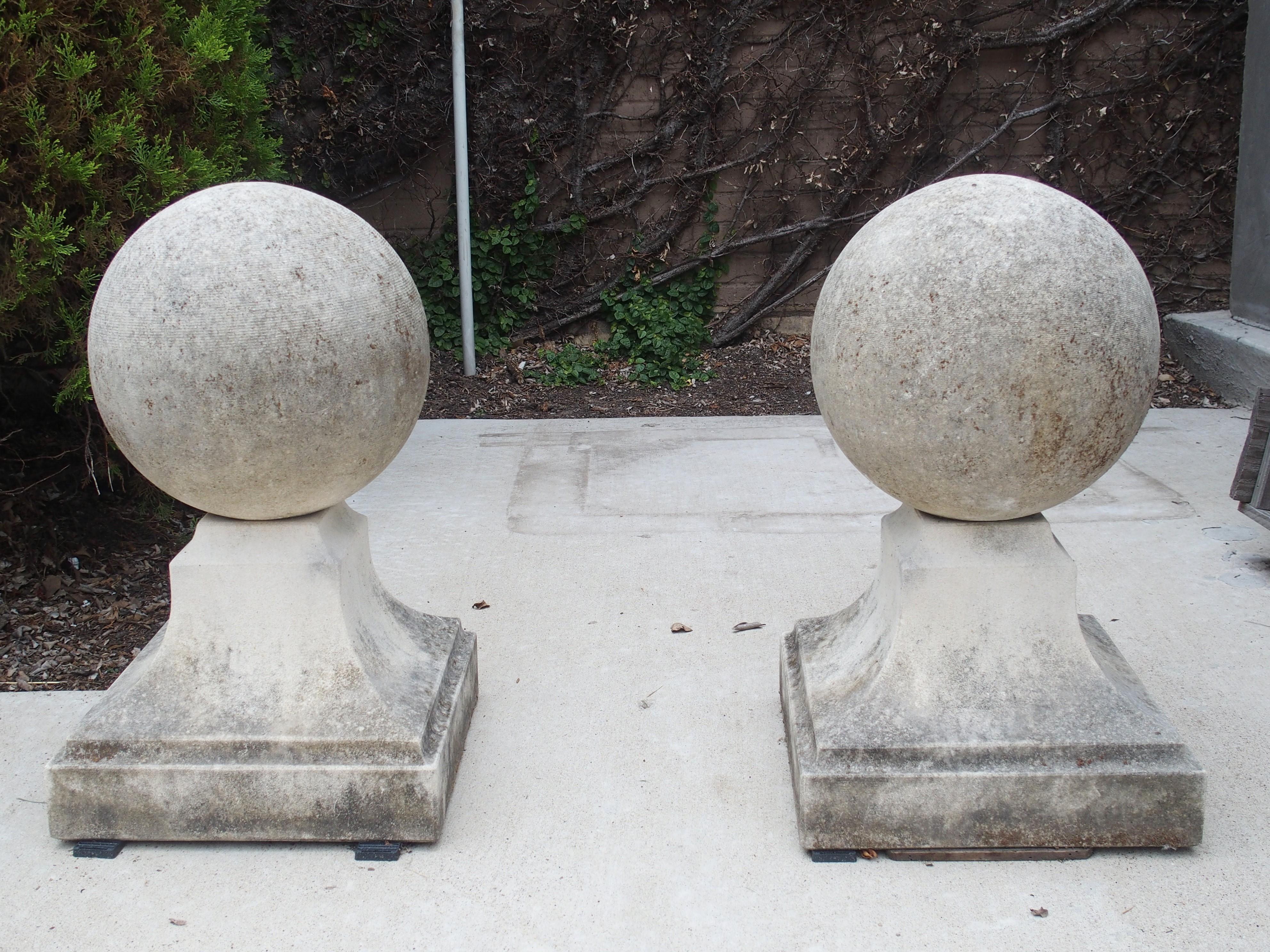 This large pair of ball finials from Italy have been hand-carved from limestone. Ball finials such as this can often be seen flanking the entry of Italian gardens. The balls are roughly 11 ¾ inches in diameter and sit atop 13 x 13 plinths. The sides
