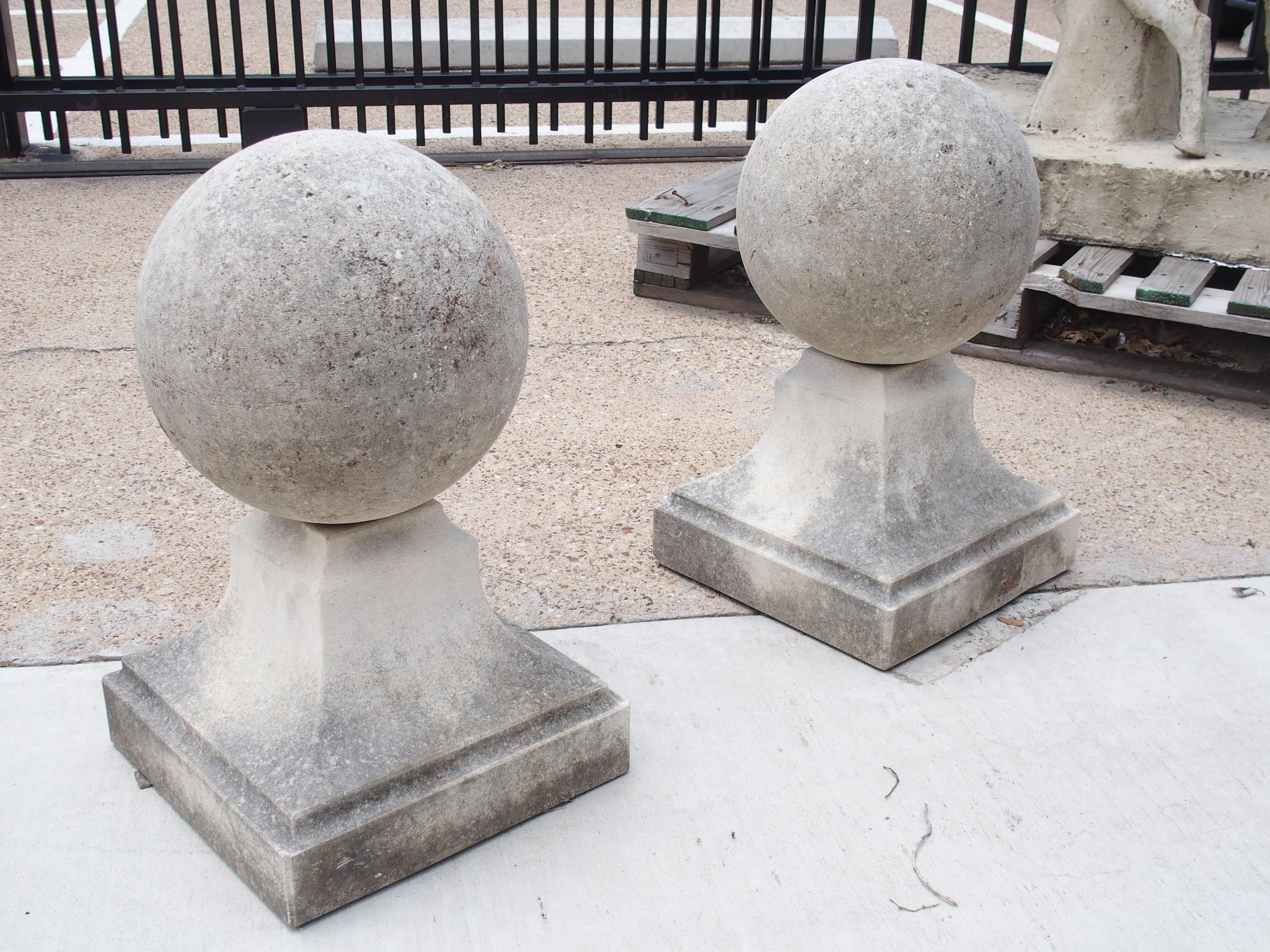 This large pair of ball finials from Italy have been hand-carved from limestone. Ball finials such as this can often be seen flanking the entry of Italian gardens. The balls are roughly 11 ¾ inches in diameter and sit atop 13 x 13 plinths. The sides