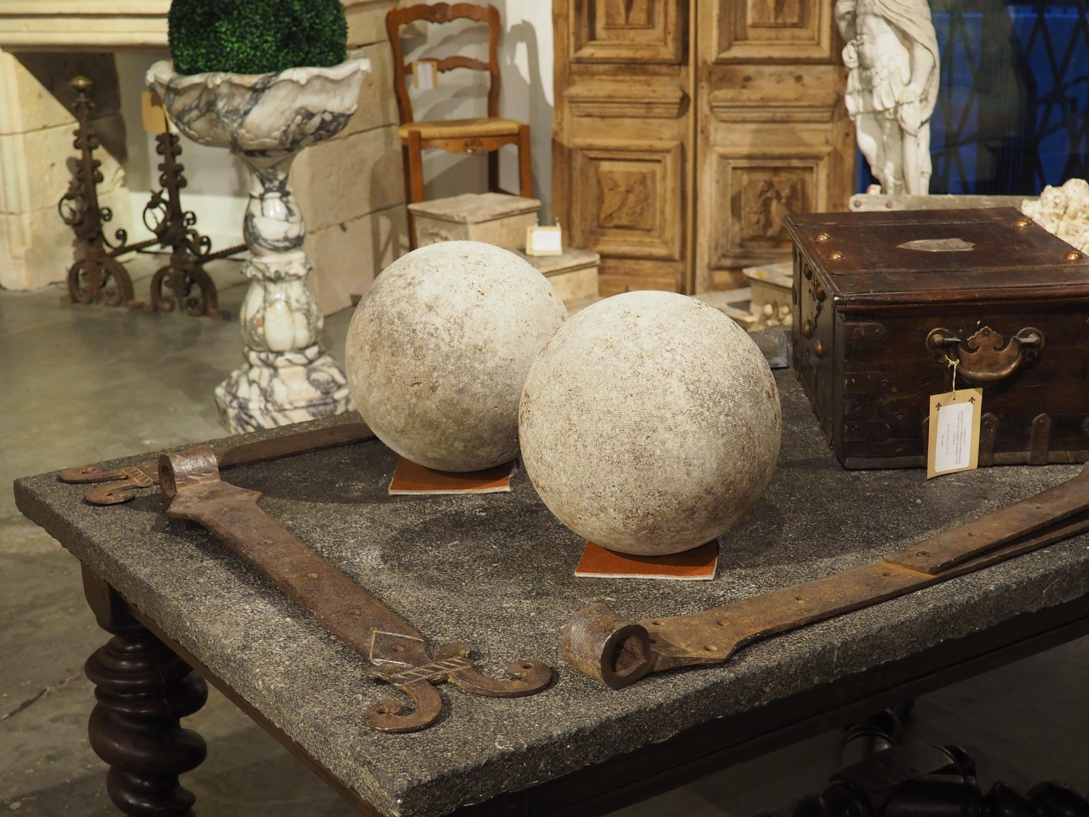 This decorative pair of garden spheres were carved from solid blocks of Italian limestone. The stones are dotted with brown lichen and green moss buildup, adding character to the nice gray patina.

The limestone garden spheres are highly versatile