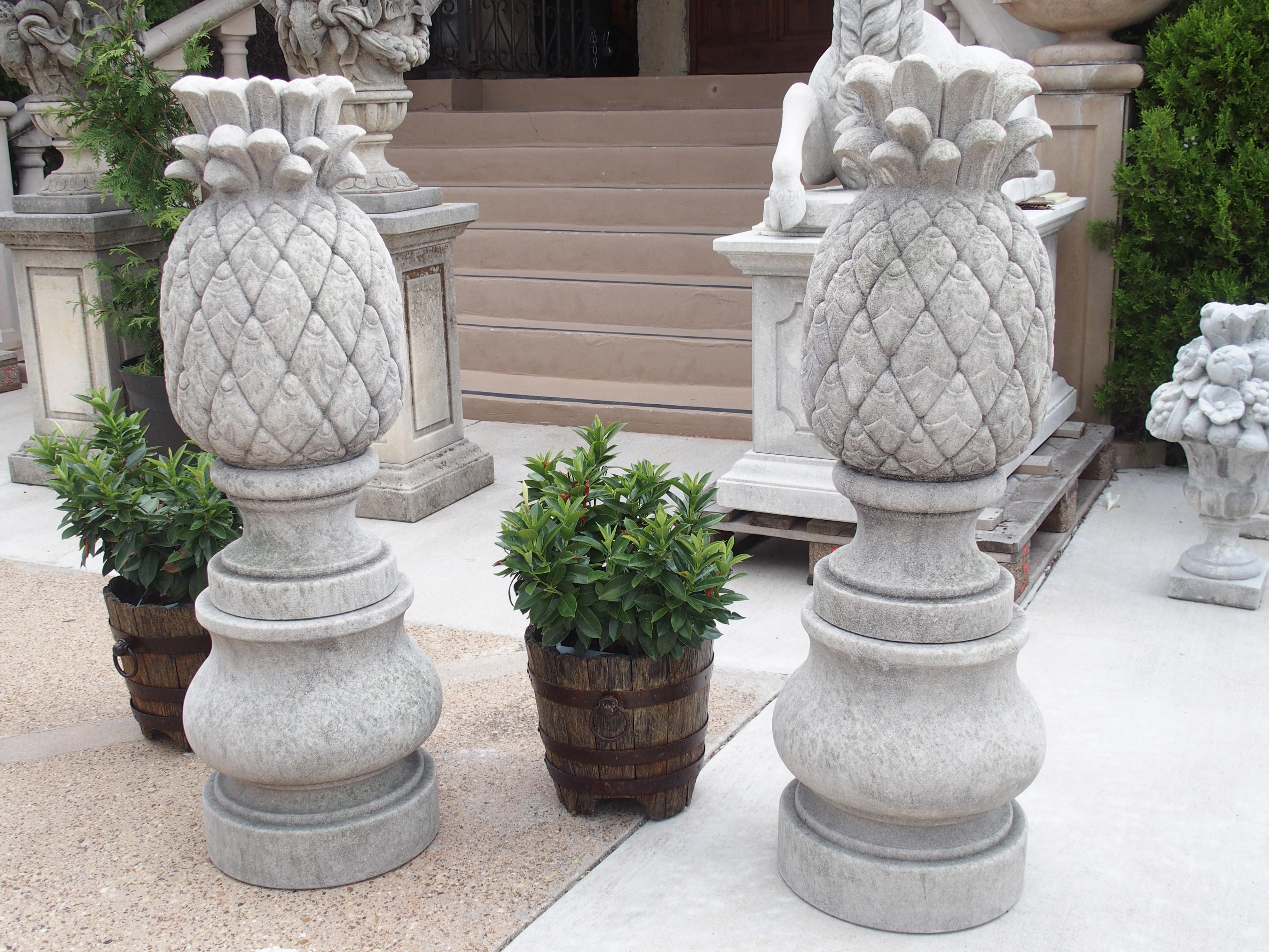 Hand-carved in Italy, this pair of limestone pineapple finials sits on 15 ¼ inch bulbous pedestals. Each pineapple has been carved from one piece of stone, which is a separate stone from the pedestals.

The amount of detail put into each carving