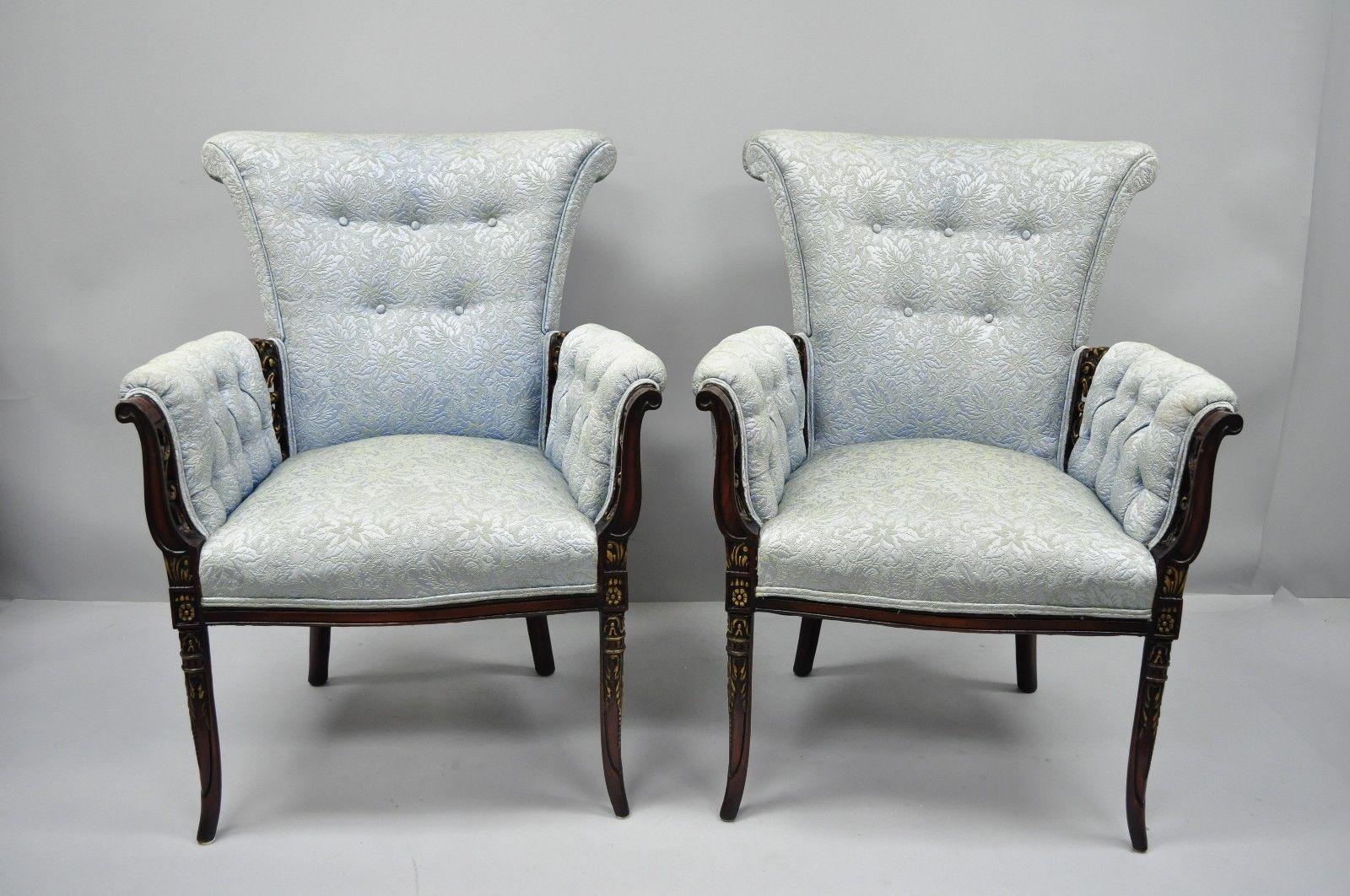 A pair of antique Hollywood Regency French style carved mahogany fireside armchairs. Listing features shapely rolled backs, blue tufted upholstery, pierce carved frames, solid mahogany wood construction, nicely carved details, tapered legs, and