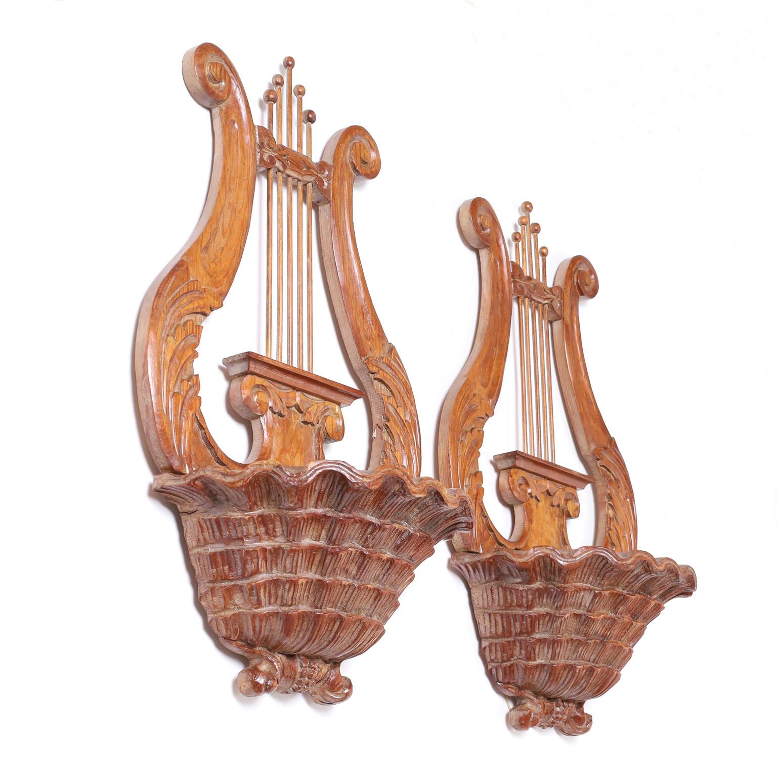 Neo classic pair of wall sconces crafted in mahogany carved in a lyre form with acanthus leaves over a cornucopia basket with a zinc lined pocket.