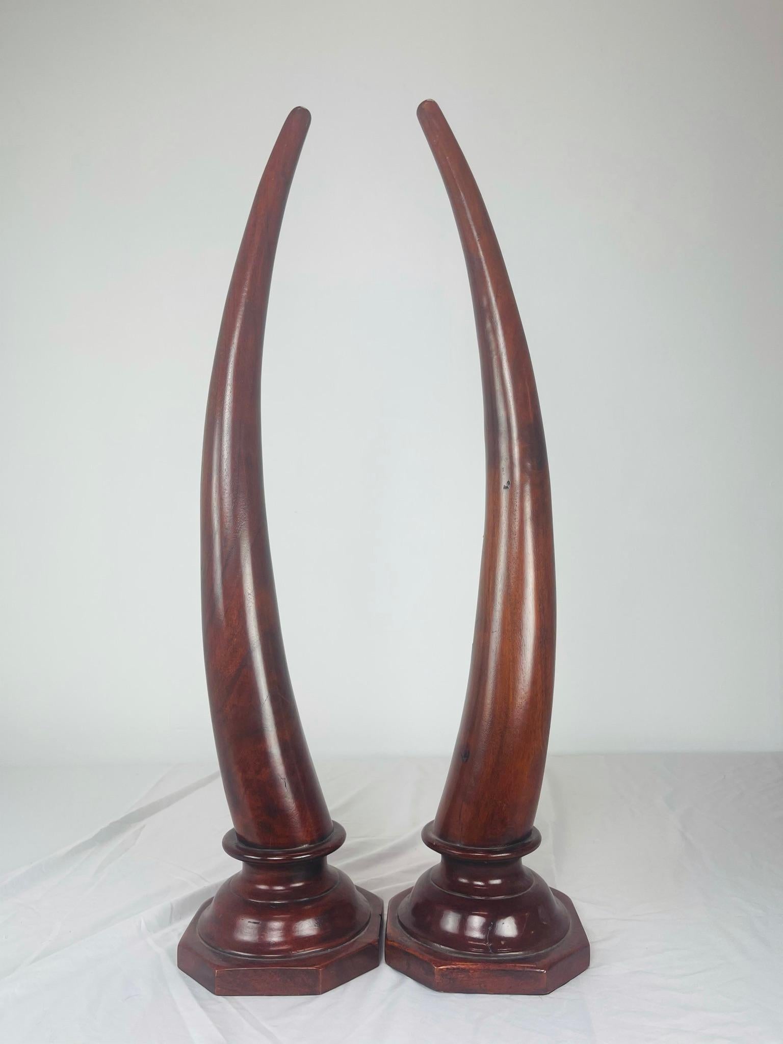 Large pair of carved mahogany faux elephant tusks on octagonal bases.