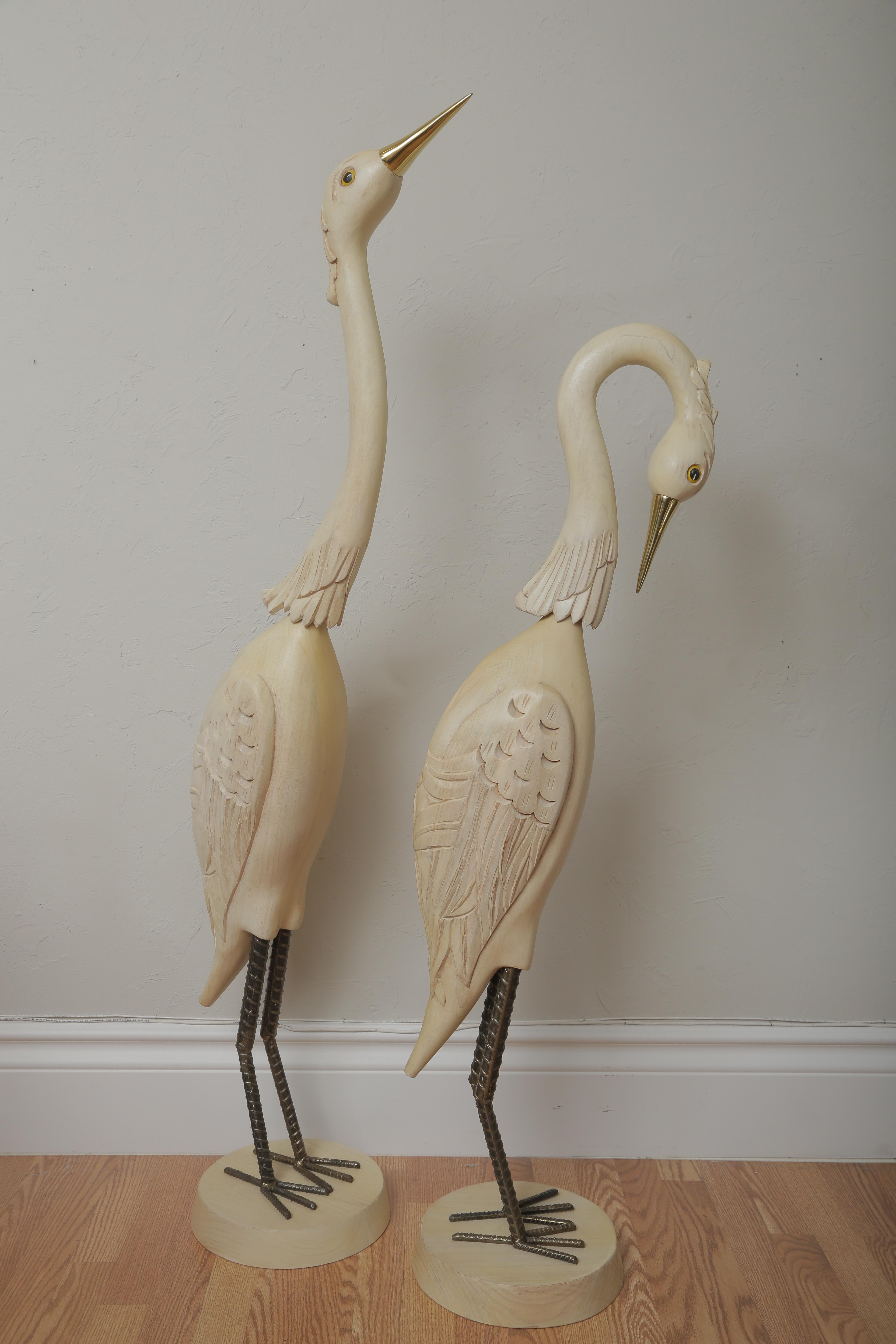Pair of large carved wood Herons with brass beaks and iron legs on round wood bases. One has head up and the other has head down.