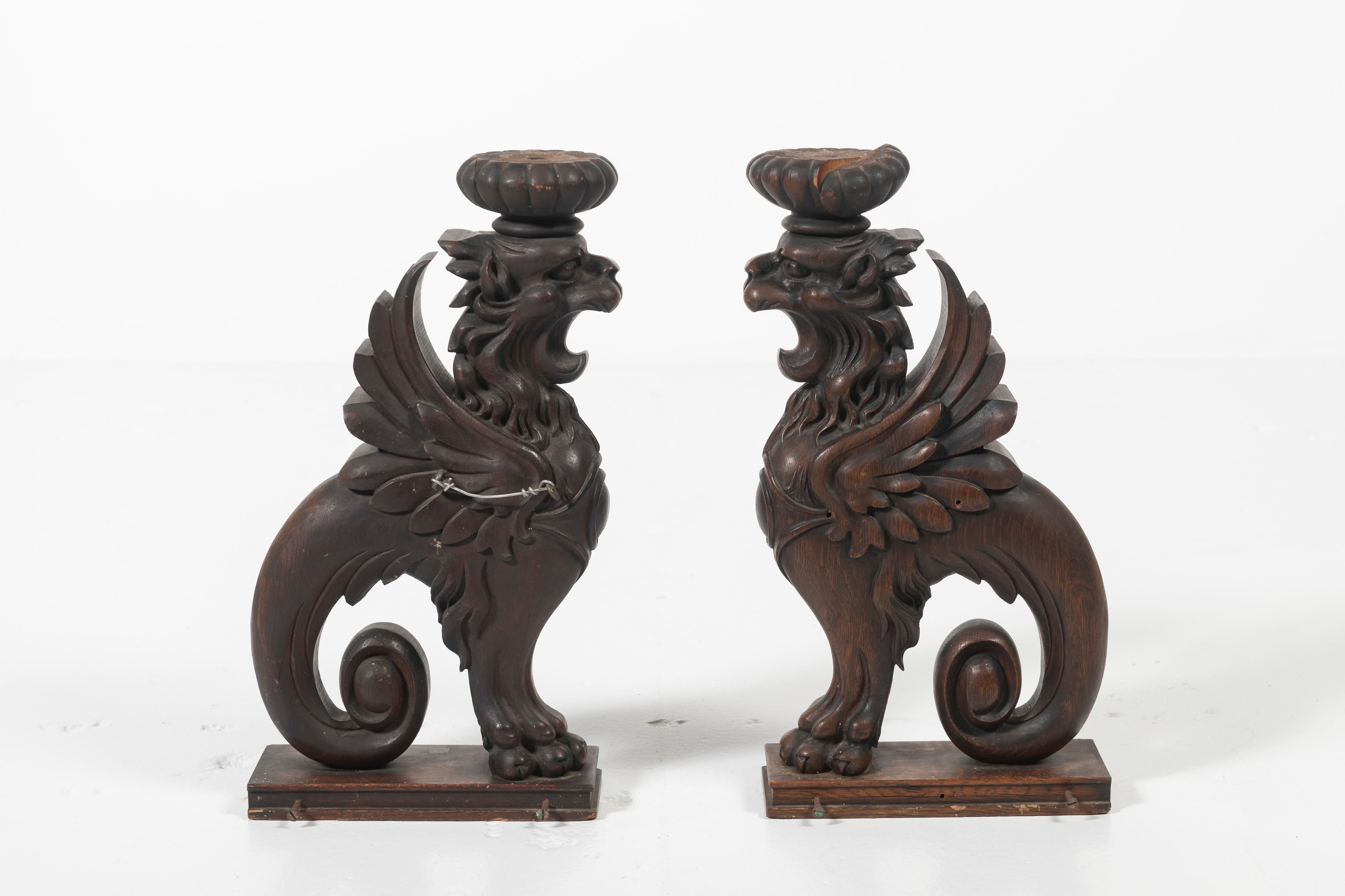 Lovely pair of antique oak carved winged Griffins circa 1900s. Good size and good condition, these artful accessories are sure to imbue the space with character and imagination. Can be fitted for candles or other items.
