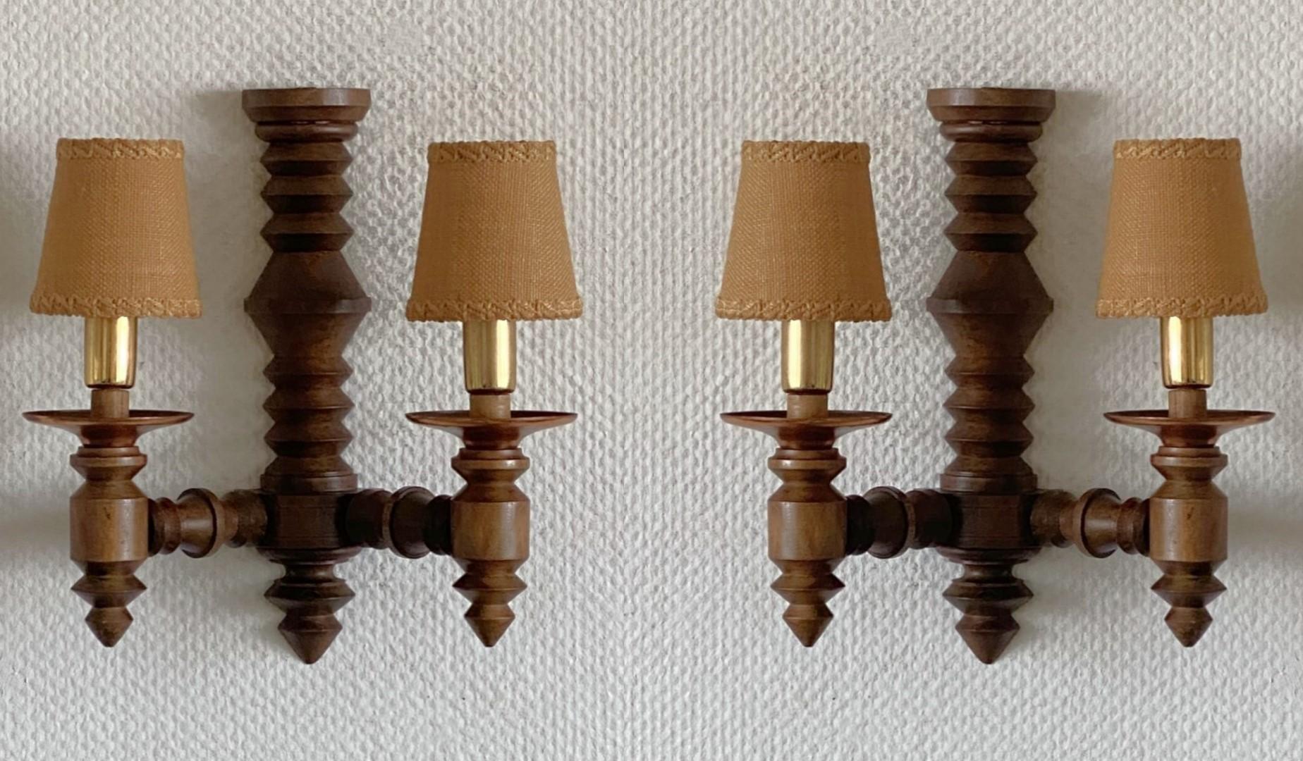 A rare pair of carved oak two-arm wall sconces by Charles Dudouyt, France 1940s. Beautiful hand-carved detailing with the original jute fabric lamp shades, two Edison E14 light sockets with brass covers. Each sconce takes two E14 candelabra screw