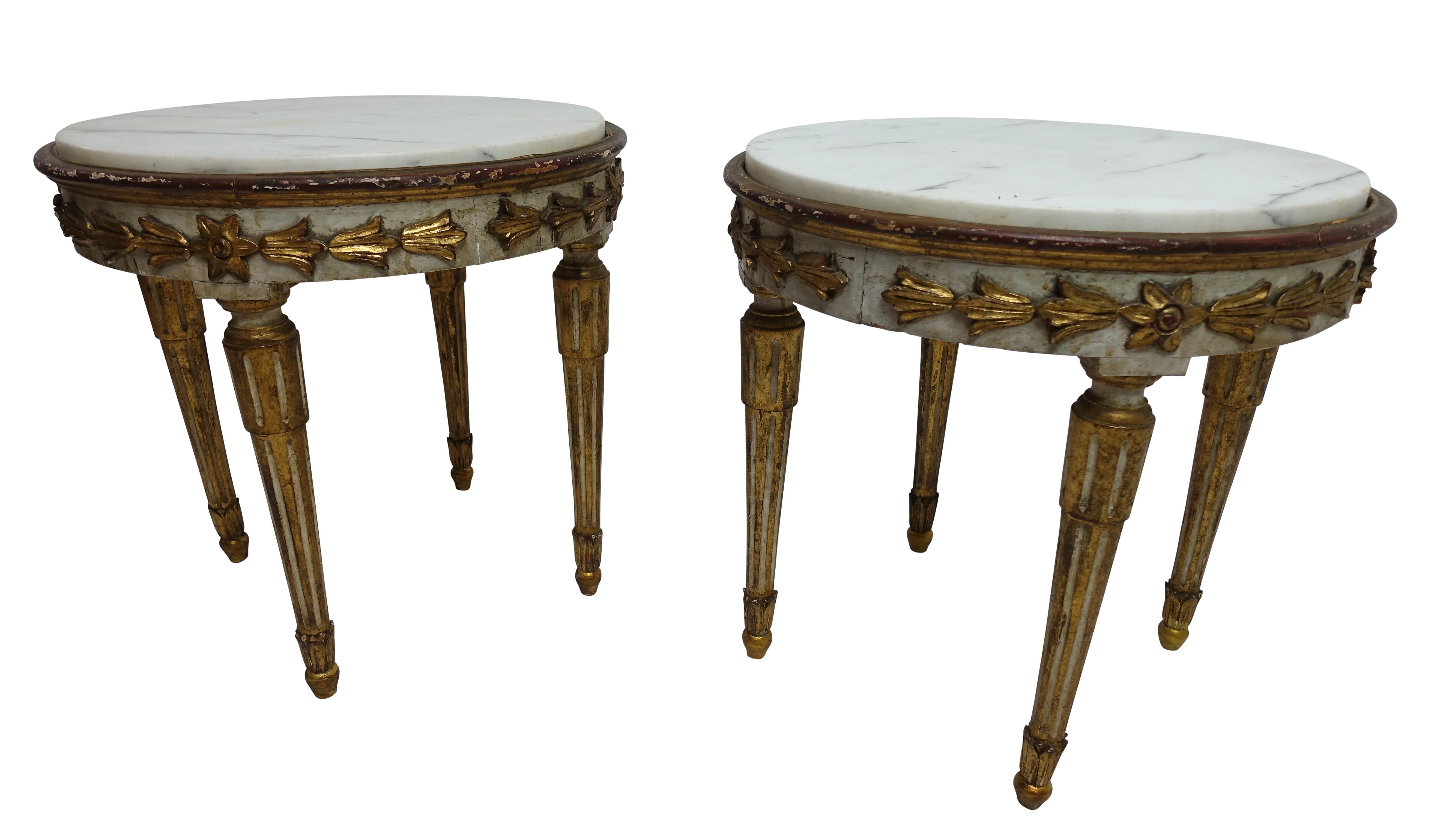 A pair of small round low side tables, painted and hand-carved with gilt floral decorations, having marble tops and standing on tapering fluted legs. Beautifully aged with expected and appropriate wear. Italian, 18th century.