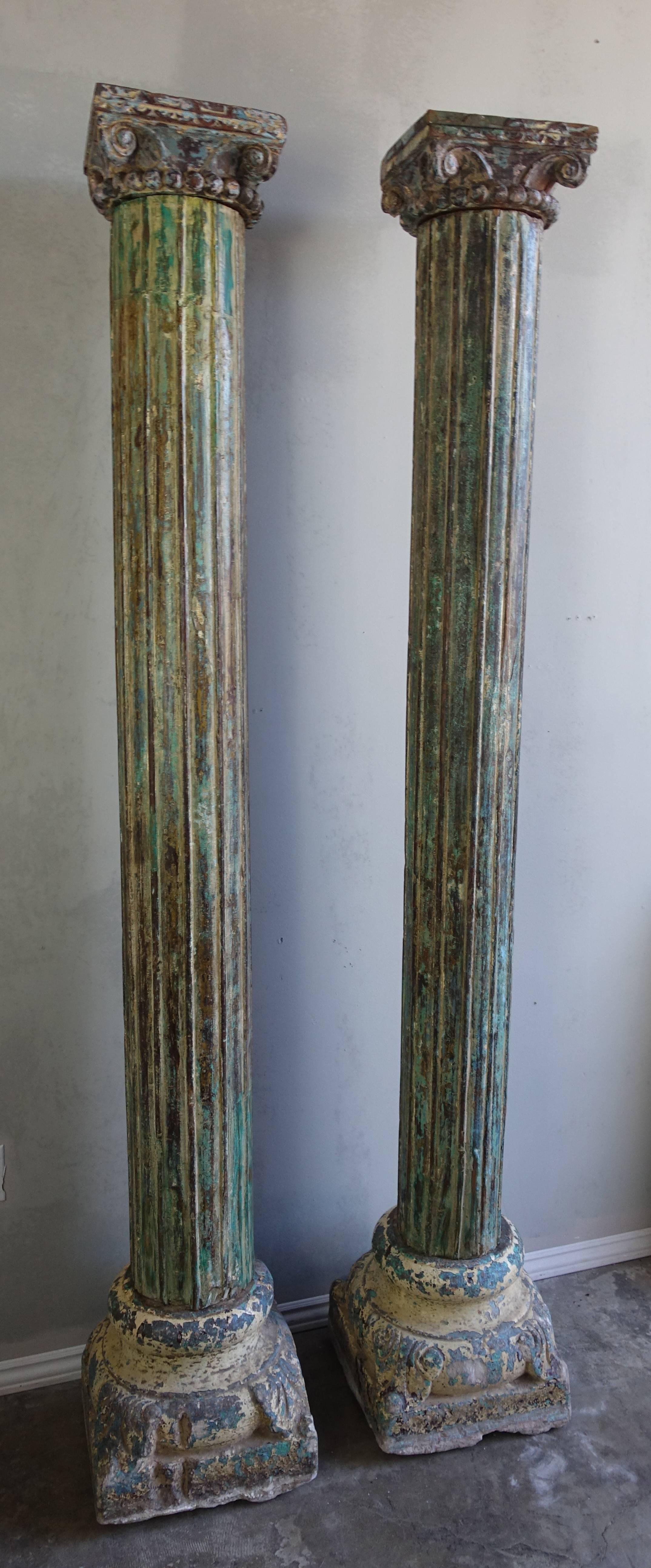 Pair of carved wood painted columns with capitals in beautiful shades of aqua, green and blue with natural wood accents showing underneath.
  