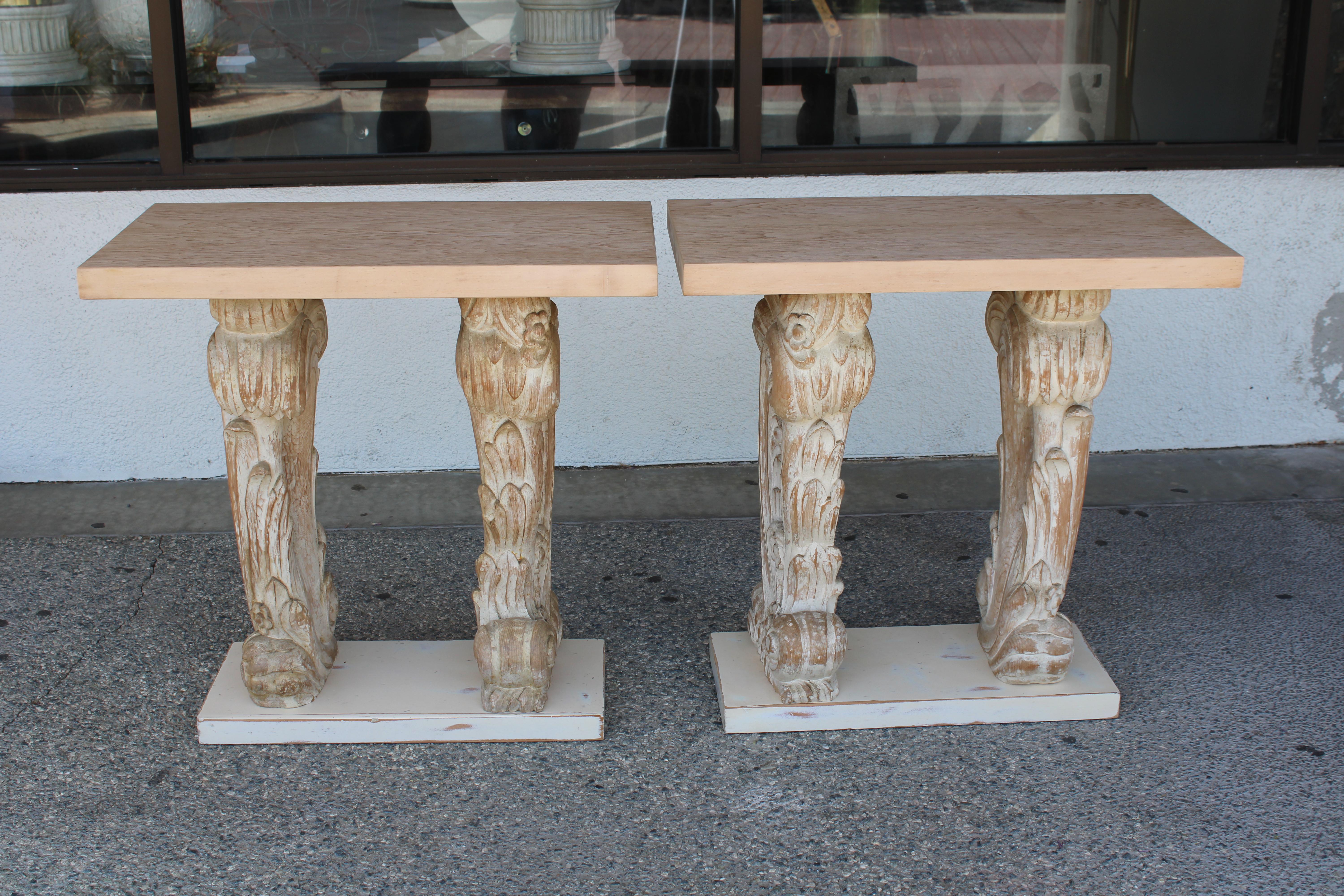 Pair of carved painted console tables. The finish is painted in soft cream muted colors. There is fine carving throughout depicting flowers and acanthus leaves. We had the painted tops professionally stripped and refinished. Each console measures