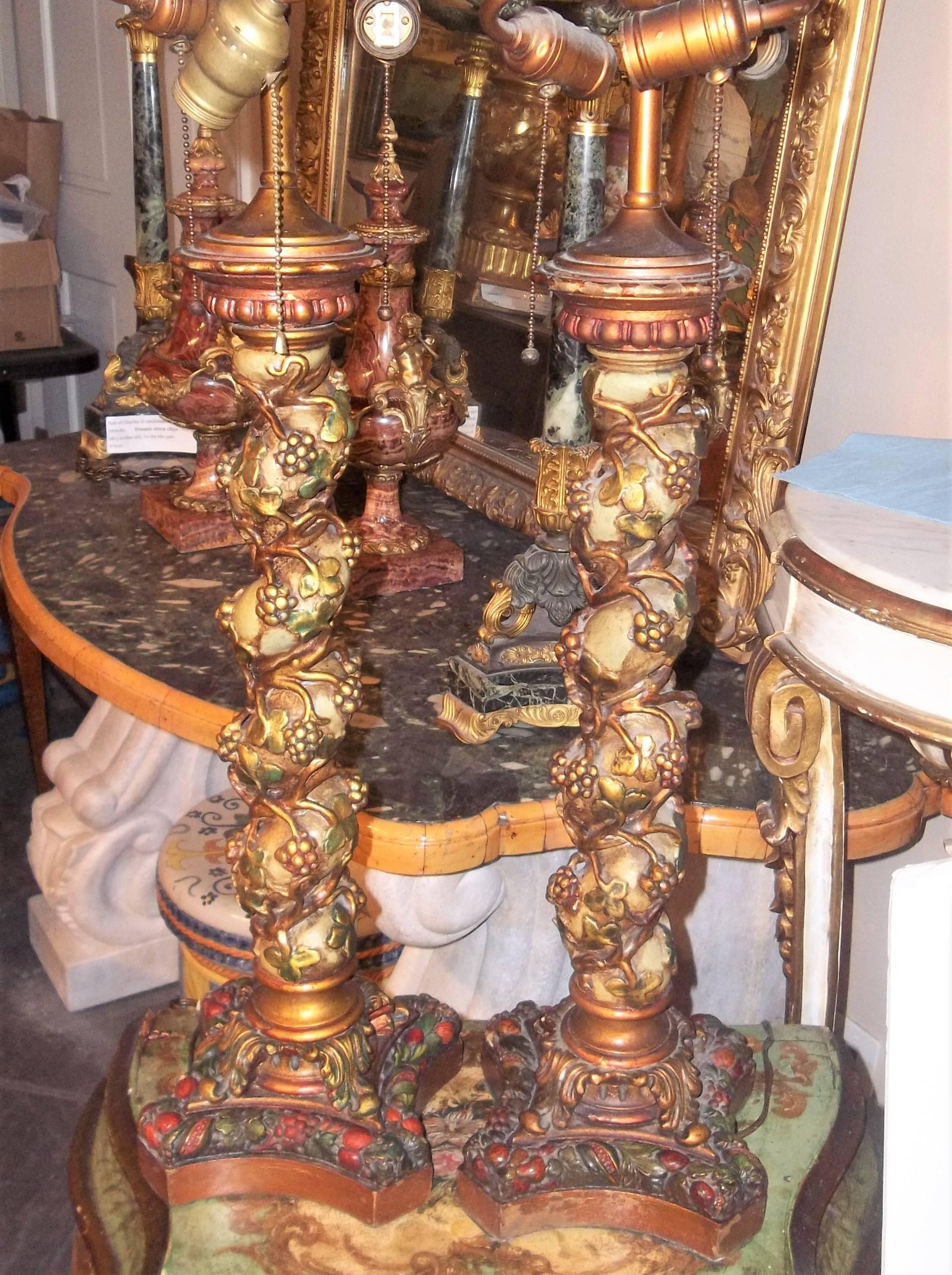 With a pale green ground with climbing grape vines. Centred upon bases of fruit and foliage .The column pretty much the same appearance all around, circa 1920s. 

Measurements of lamps including fittings 33.5 inches, base 7 inch square
Column and