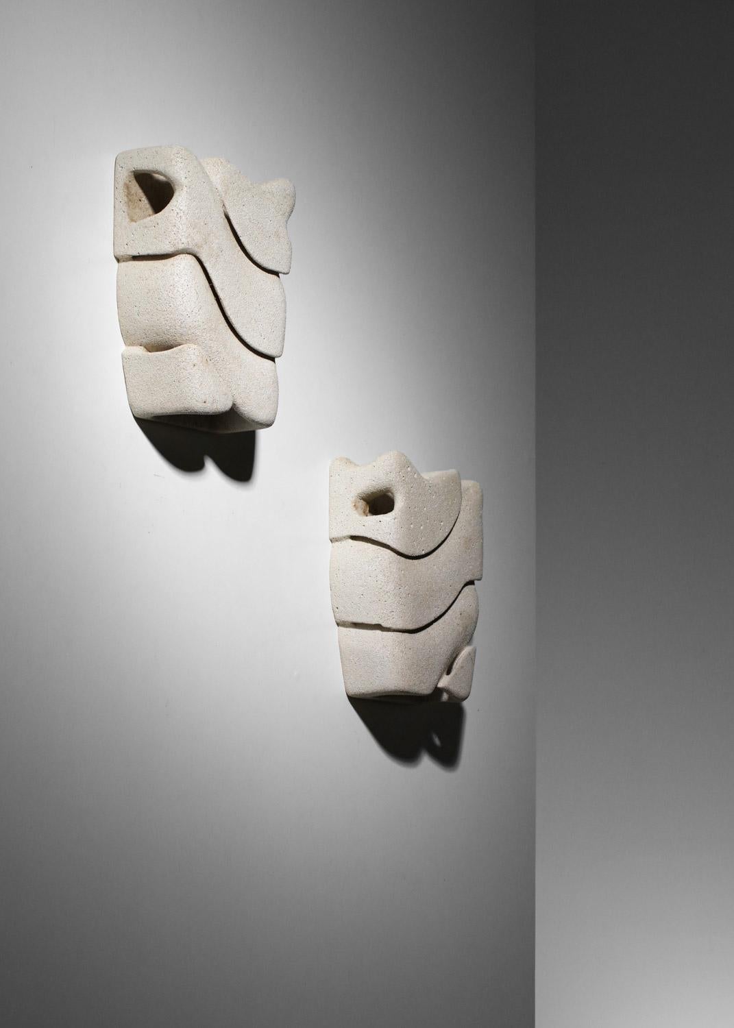 Pair of French wall lights from the 1970s/1980s in carved beige cellular stone. Very original design and shape. Very good vintage condition, some signs of age and small stains (see photos). Signature on the ceramic: HP. Independent sockets for the