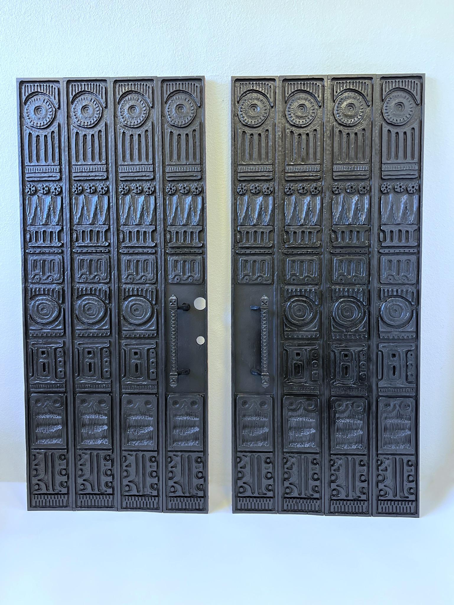 Incredible 1960’s carved redwood panels for entry doors by Evelyn and Jerome Ackerman. Designed to go over a double entry doors. Four panels with frame for each door. The door pulls are powder coated cast aluminum. 

In beautiful vintage condition.