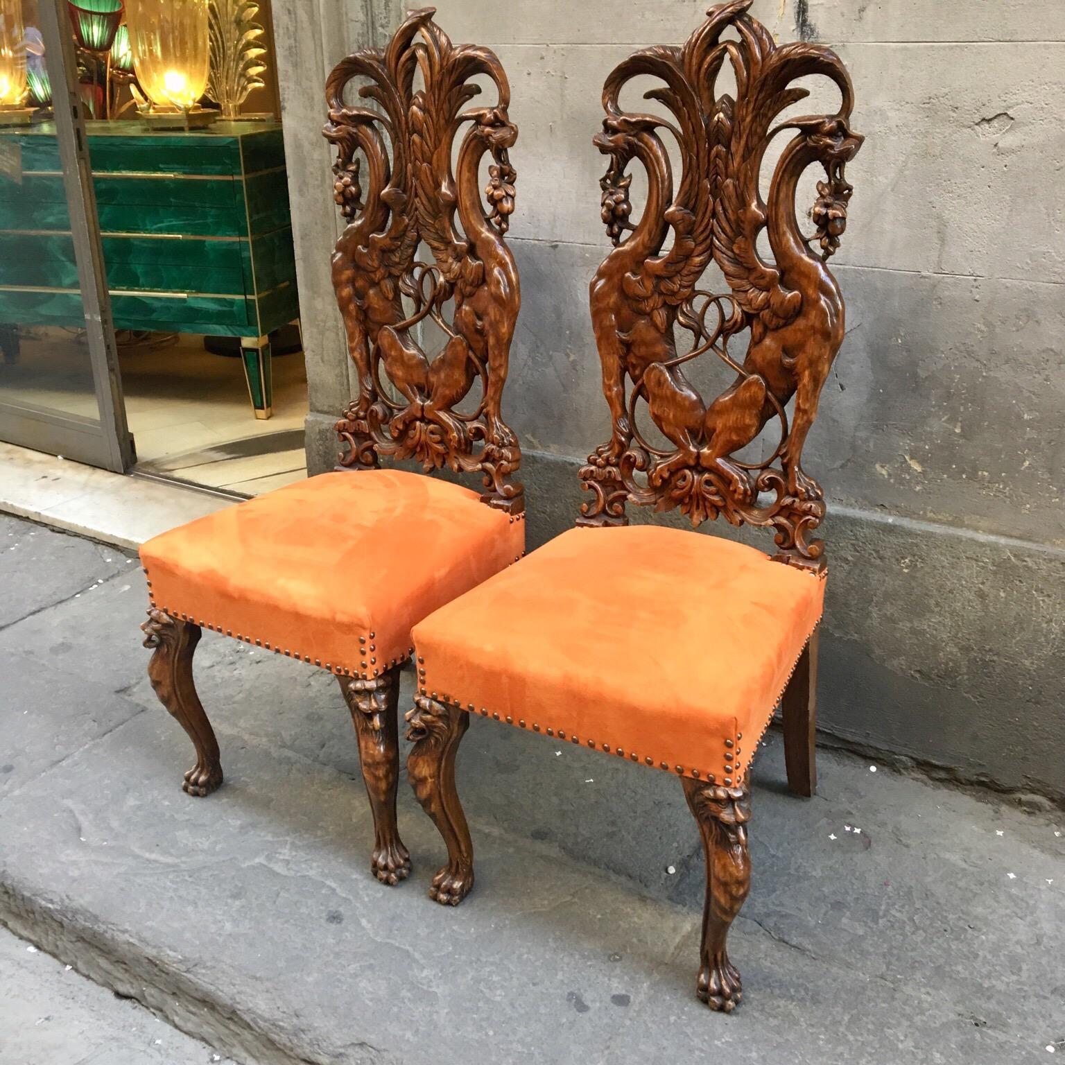 Pair of hand carved Renaissance-style wooden chairs. The back of the chair is made of mahogany wood carved subject Renaissance Florentine art. Newly-upholstered seat with orange alcantara, stain-resistant fabric by Dedar.