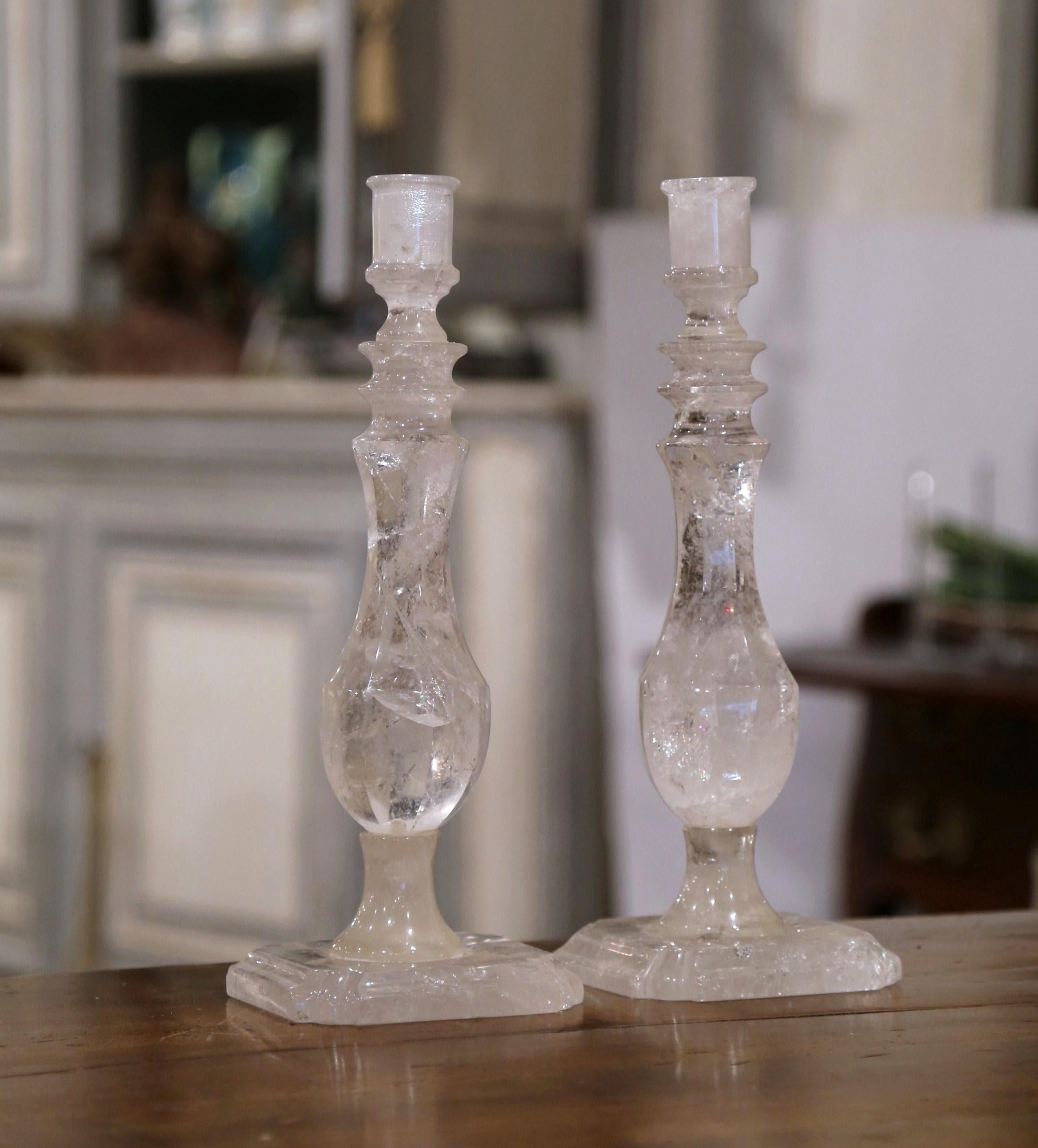 This elegant pair of rock crystal candlesticks was crafted in Brazil. Each candleholder sits on a sturdy, square base and features exquisite craftsmanship throughout. The candlesticks have a carved stem with an octagonal center base. Both pieces are