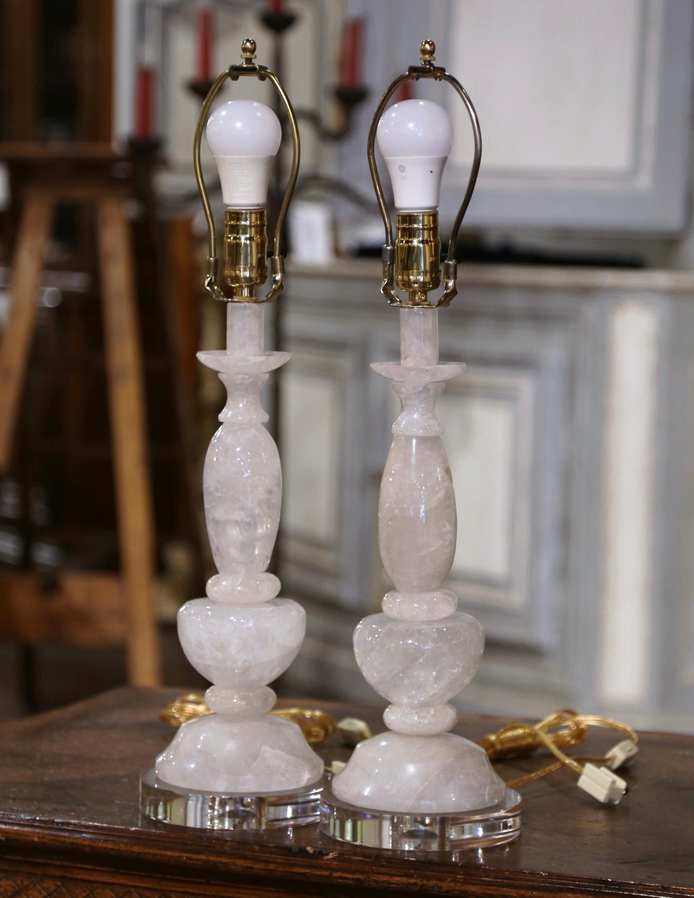 Bring elegance to your formal living room or den with this sophisticated pair of rock crystal table lamps. Crafted in Brazil, and standing on clear round acrylic bases, the hand carved lamps with turned stems have been outfitted with new wiring.
