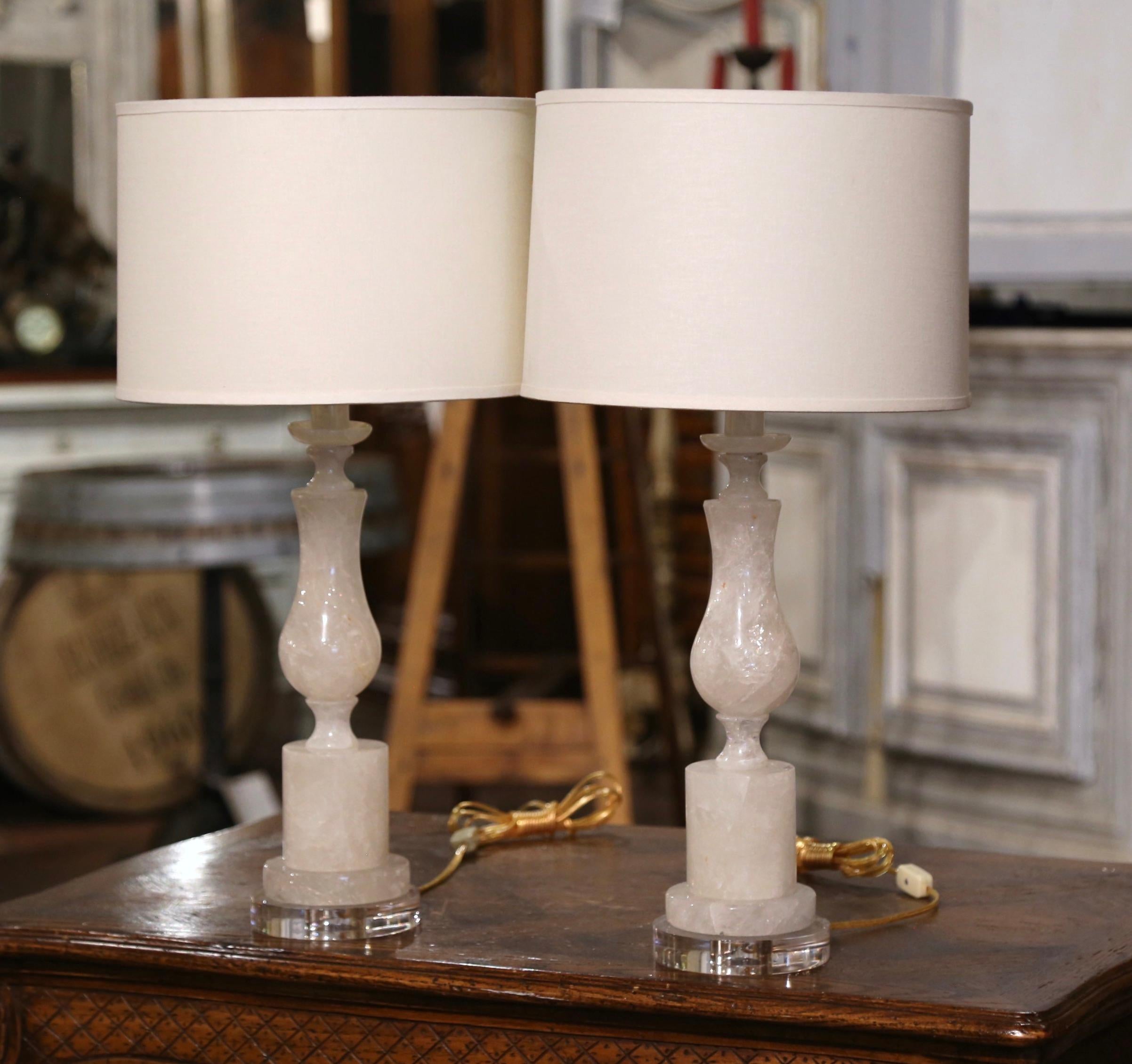 Bringen Sie Eleganz in Ihr formelles Wohnzimmer oder DEN mit diesem raffinierten Paar Bergkristall-Tischlampen. Die in Brasilien gefertigten, handgeschnitzten Lampen mit gedrechselten Stielen stehen auf klaren, runden Acrylsockeln und wurden mit