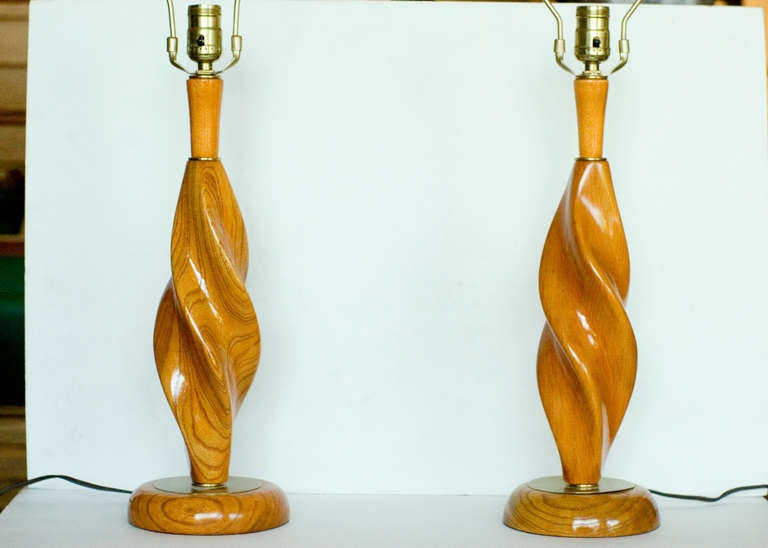 A lovely pair of hand carved oak spiral table lamps with brass accents. The oak has been hand polished to highlight the beautiful grain of these lamps.