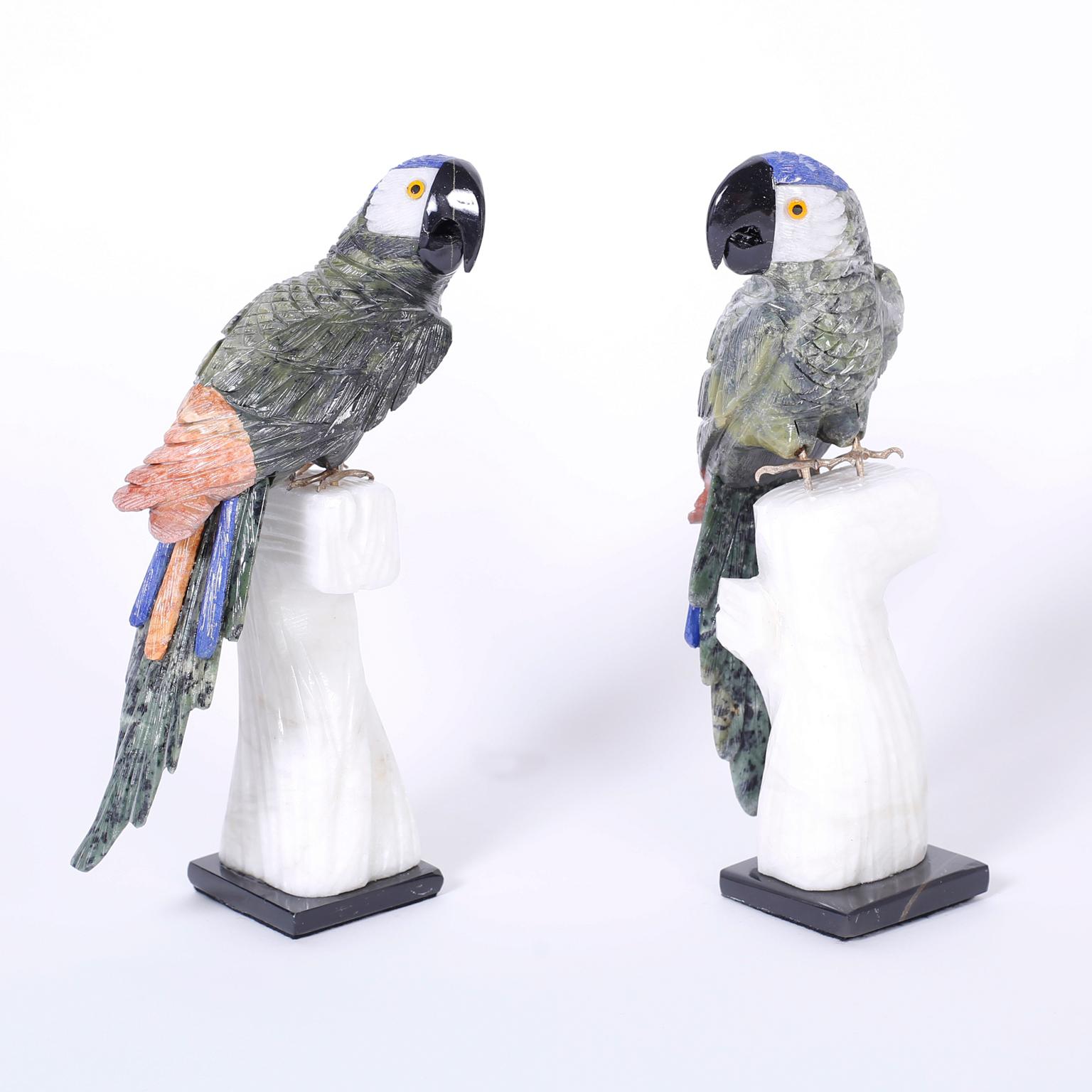 Pair of birds carved from various semiprecious stones with an amusing expression and brass feet perched on carved stone tree trunks.