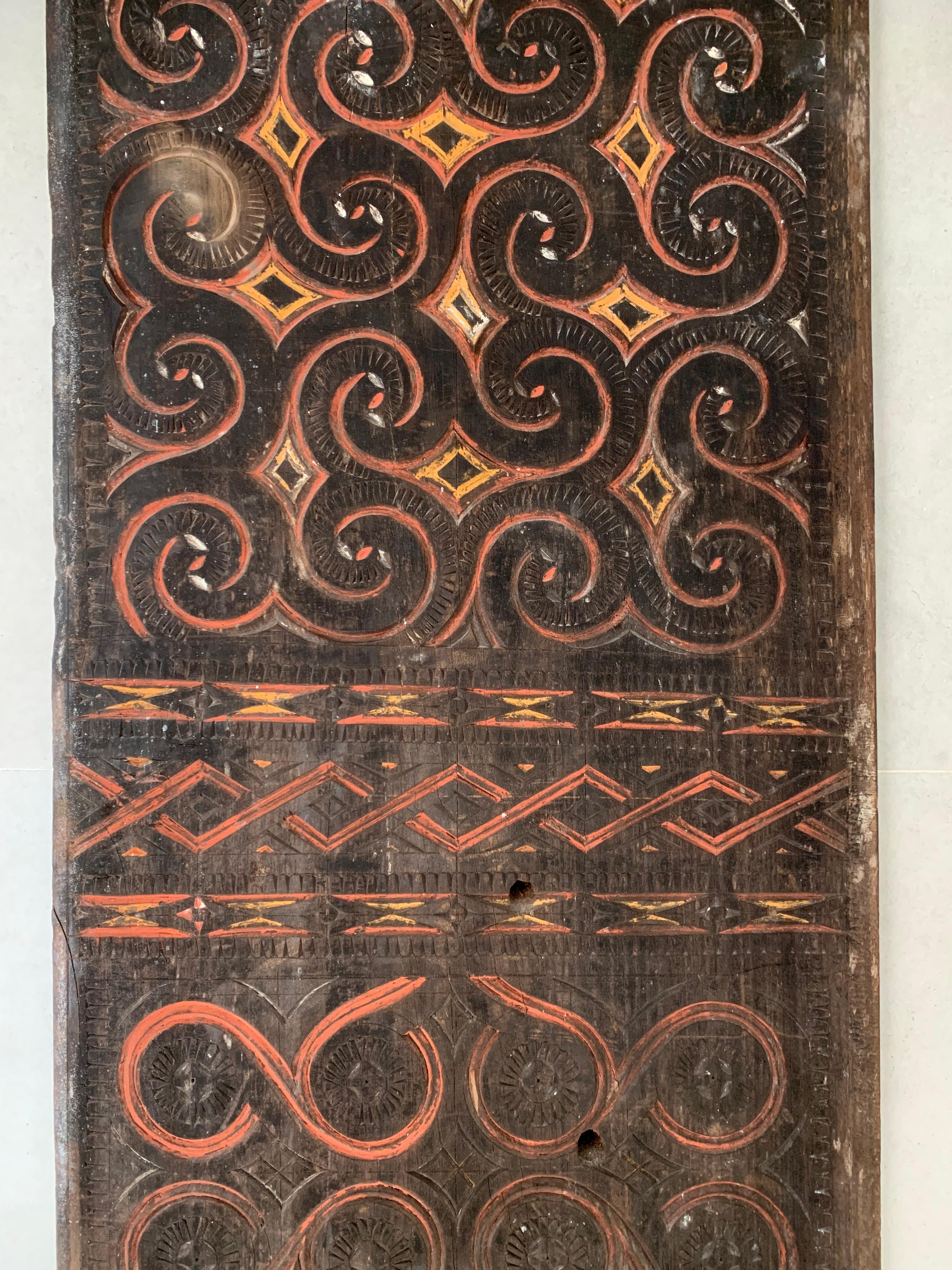 Thes decorative panels, carved from Uru wood once occupied the exterior of a traditional Torajan ancestral house. They feature red, white, orange and black pigment. Their aging is present in the deterioration in pigment and wood from having occupied