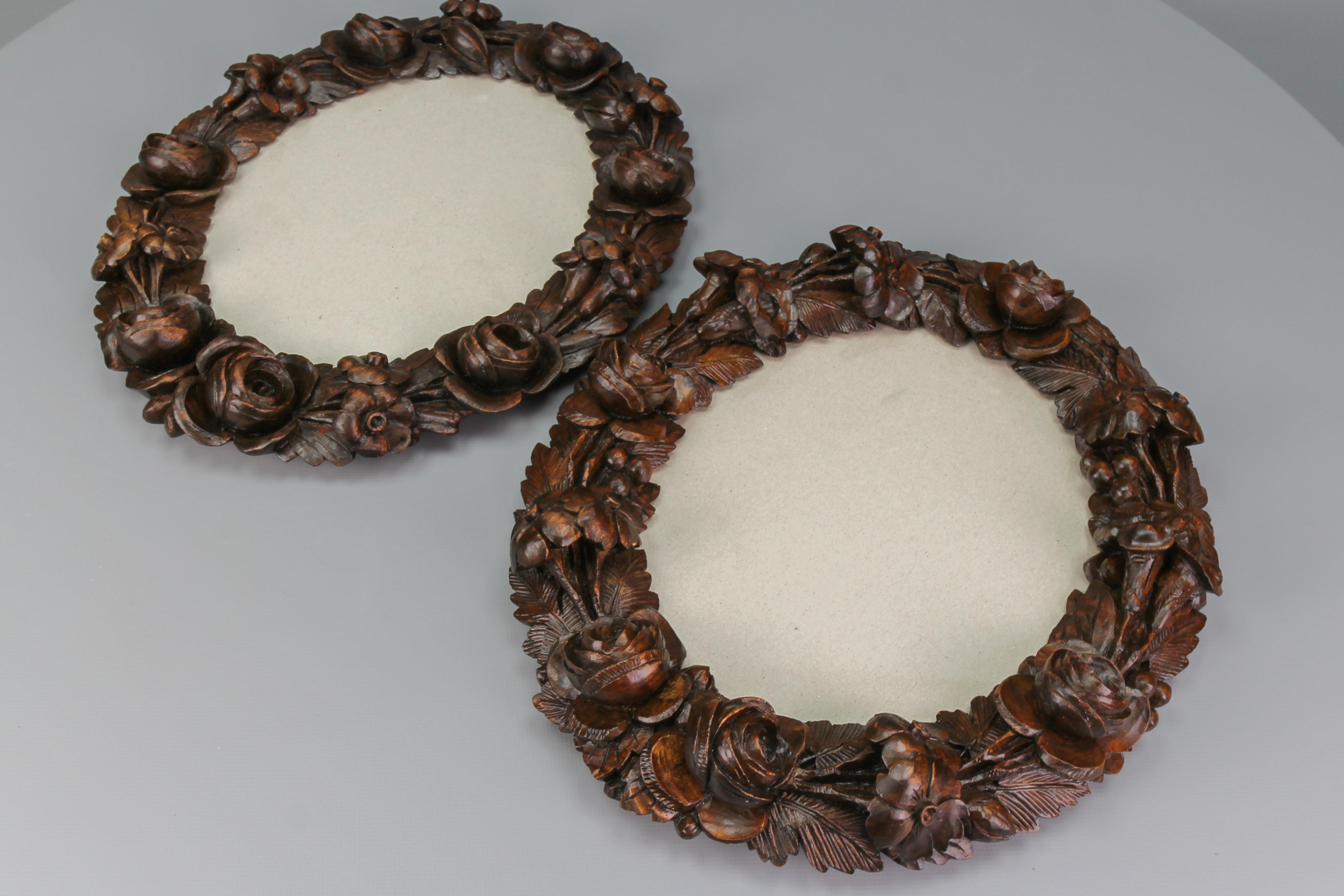 Pair of finely carved walnut oval dark brown wall picture or photo frames with flowers and leaves, Austria, ca. 1920.
The impressive pair of frames is masterfully carved throughout with a variety of interlocking flowers and foliage and has a glass