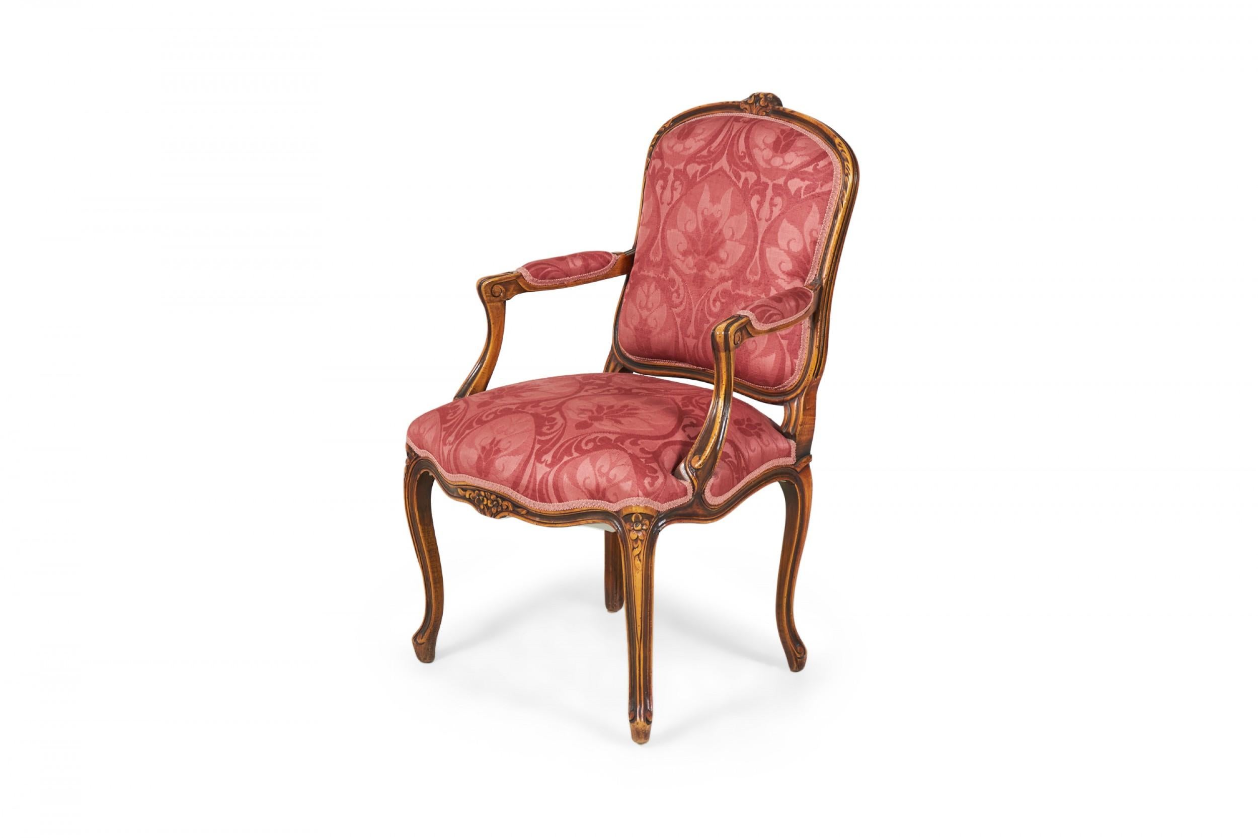 COPPIA di poltrone francesi in stile provinciale Luigi XV (seconda metà del XX secolo) con struttura in noce intagliato e schienale a cresta con tappezzeria damascata rosa e rossa. (PREZZO IN COPPIA)