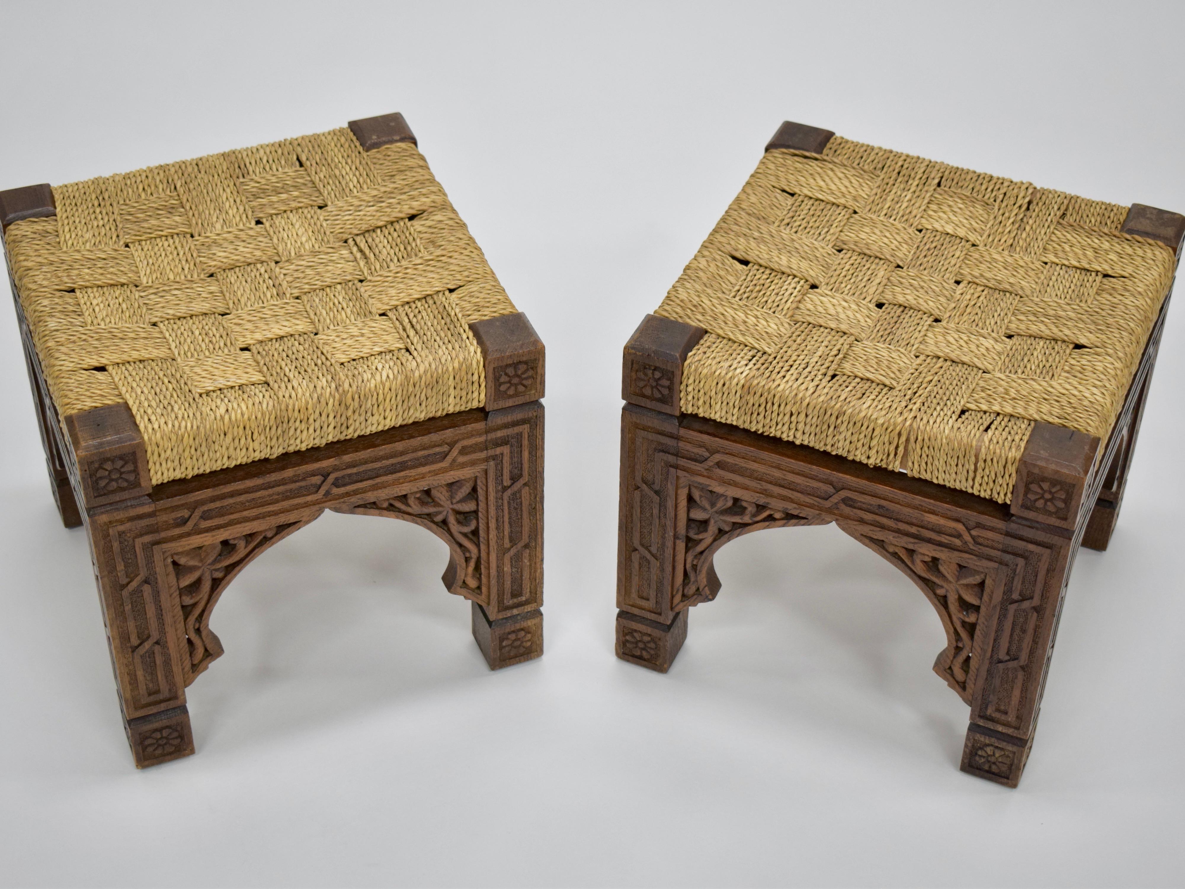 A pair of beautiful square carved wood stools with woven Danish cording seats. Found in France. The seats were crafted using a classic grid weave, while the intricate carvings on the base evoke Moroccan archways and floral motifs. 

