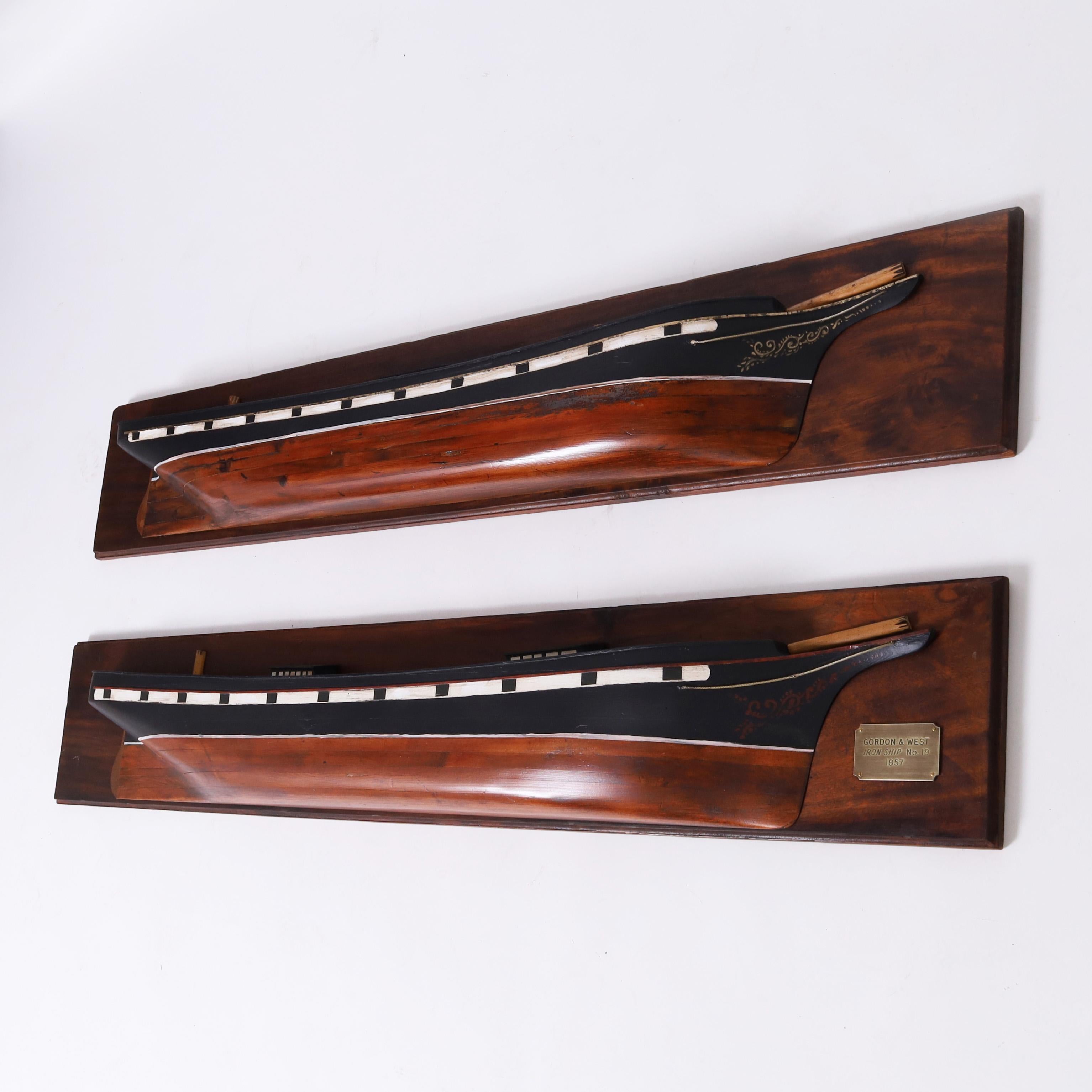 Impressive pair of mirror image antique half hull models crafted in pine, paint decorated, and faithfully rendered in form to early iron ship hull designs and mounted on mahogany plagues.
