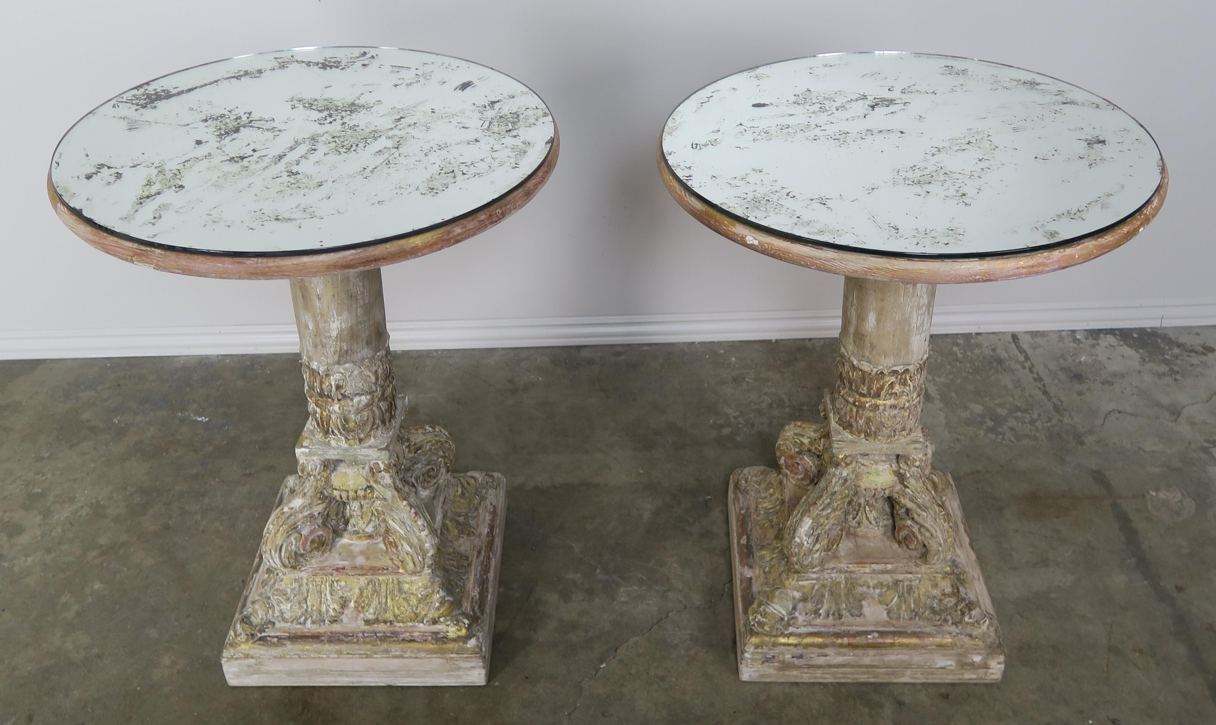 Pair of carved wood and parcel gilt side tables with antiqued mirrored tops. The tables have a beautiful worn finish with remnants of gold leaf on the raised portions of the carving.