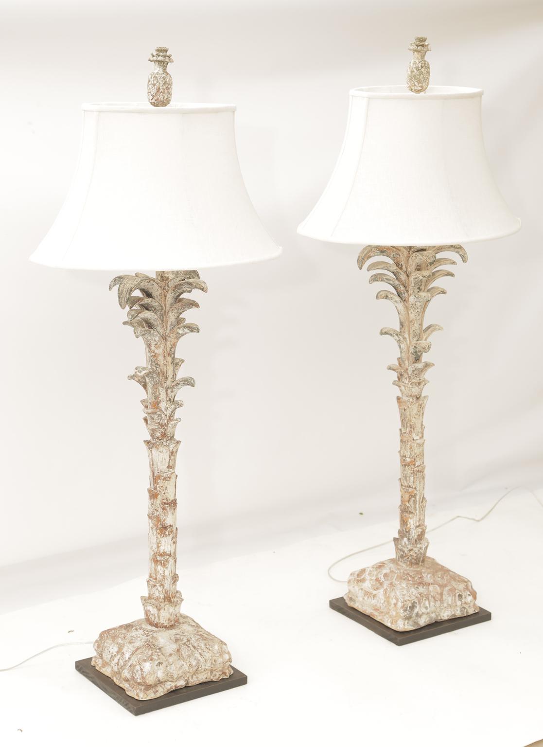 Pair of large table lamps, of carved wood, having a distressed, painted finish; each having a foliate 