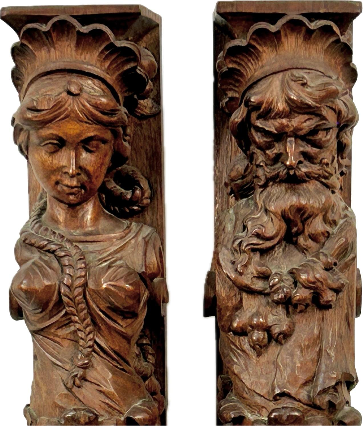 Pair of delicately carved wooden architectural fragments. Fragments feature a column-like shape with a male and female head near top and cherubs carved mid way down. Fragments are supported on claw feet that add a touch of elegance and historical