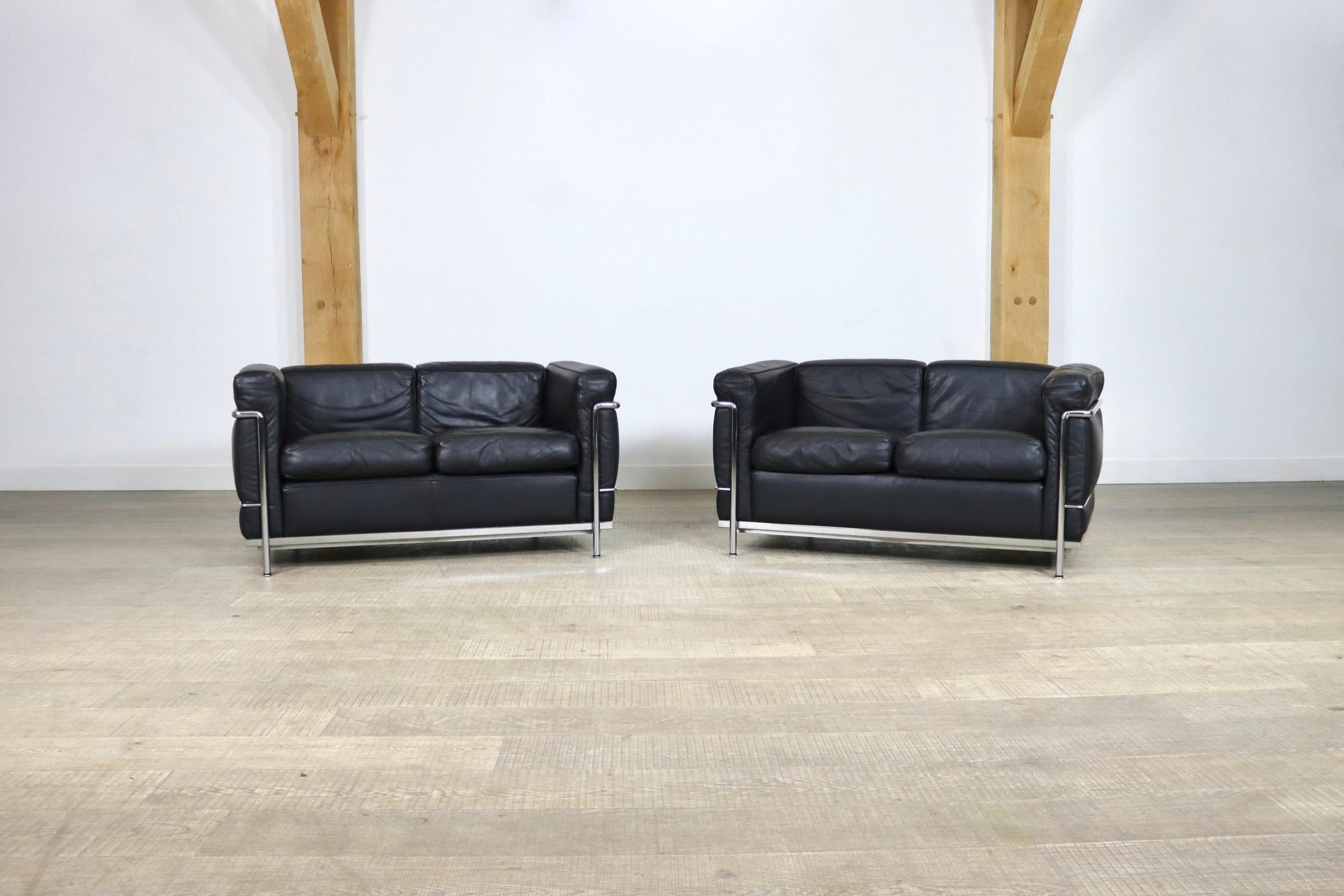 Amazing pair of LC2 two seater sofas, a true design classic by Le Corbusier, Pierre Jeanneret and Charlotte Perriand, originally designed in 1928. The modern sofa is composed of a tubular chrome frame and high-end black leather cushions. Both sofas