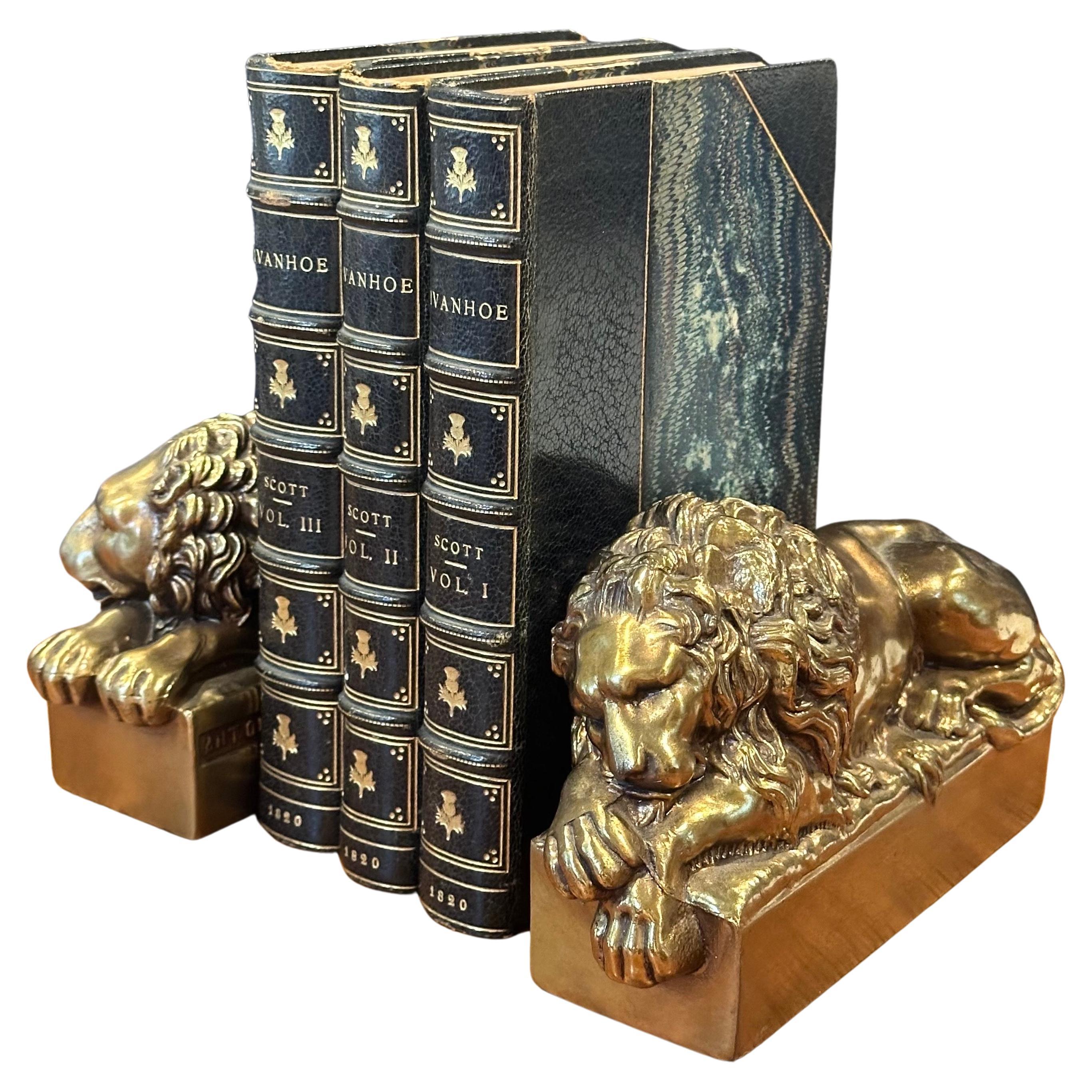 Pair of cast brass lion bookends by Antonio Canova, circa 1940s.  These lions were originally sculpted by Antonio Canova (Italian, 1757-1822) in larger scale for the tomb of Pope Clement XIII in St. Peter’s Basilica. The Sleeping lion pictured is