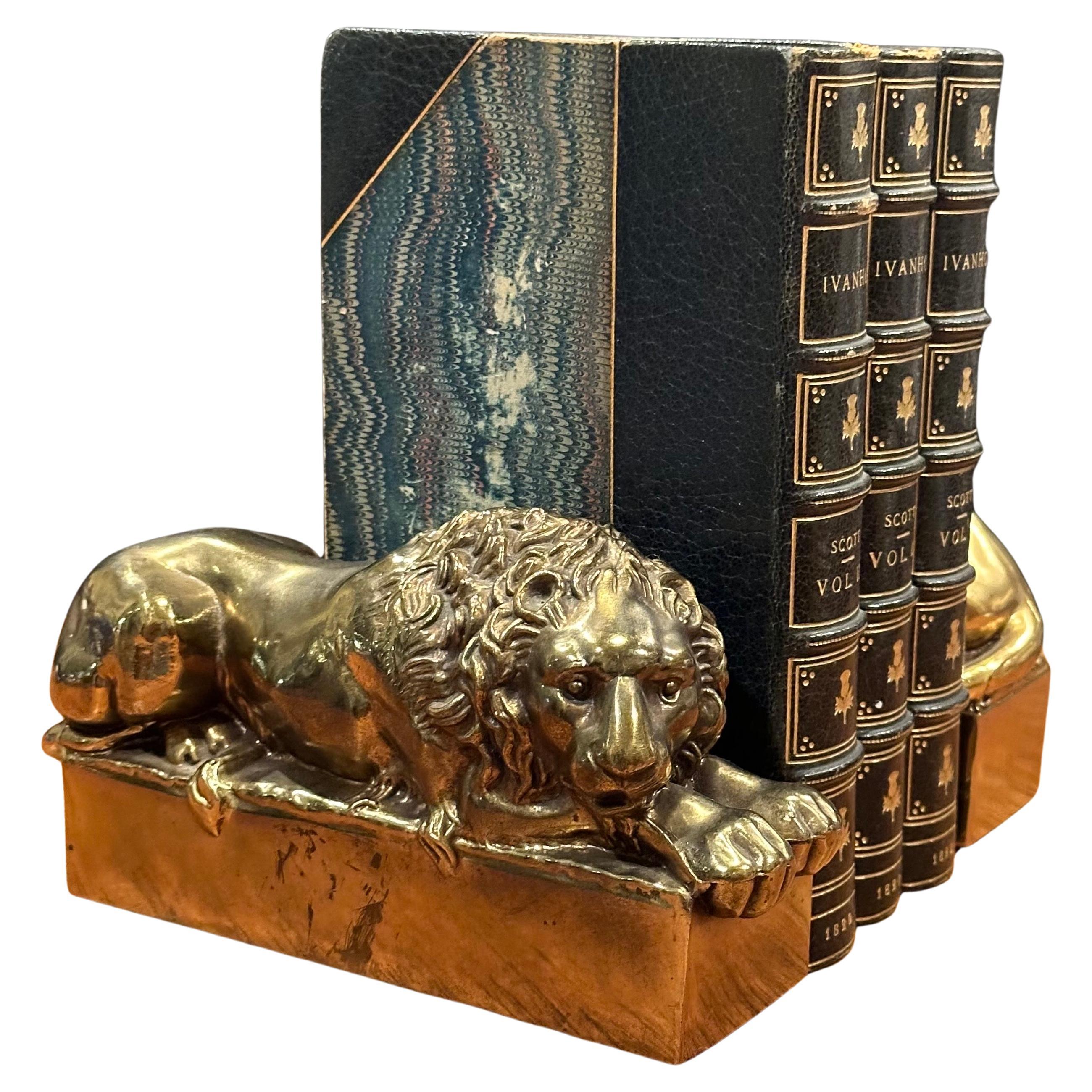 Pair of cast brass lion bookends by Antonio Canova, circa 1970s.  These lions were originally sculpted by Antonio Canova (Italian, 1757-1822) in larger scale for the tomb of Pope Clement XIII in St. Peter’s Basilica. The Sleeping lion pictured is