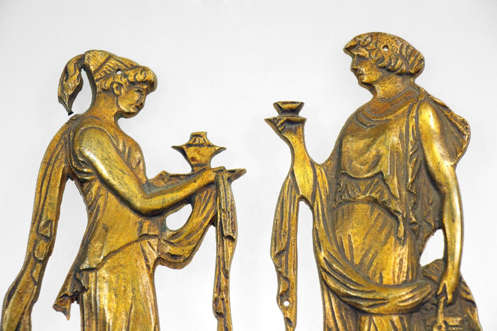 A detailed cast brass set of artistic Roman figures furniture accents from Belgium. These accents can be anchored to a furniture piece to add interest or can be used in other possible artistic applications.