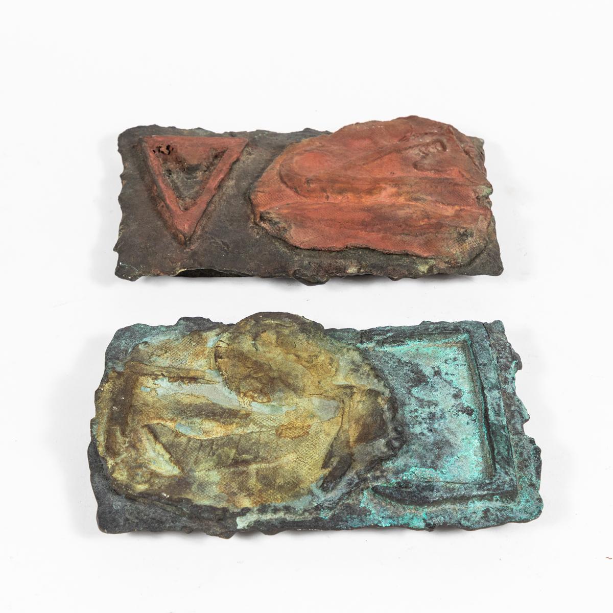Pair of cast bronze Brutalist plaques with red, blue, and green painted decoration. The tactile nature of the piece makes a wonderful contrast with its rough-hewn industrial materials. A uniquely sculptural accent, these can be hung or displayed as