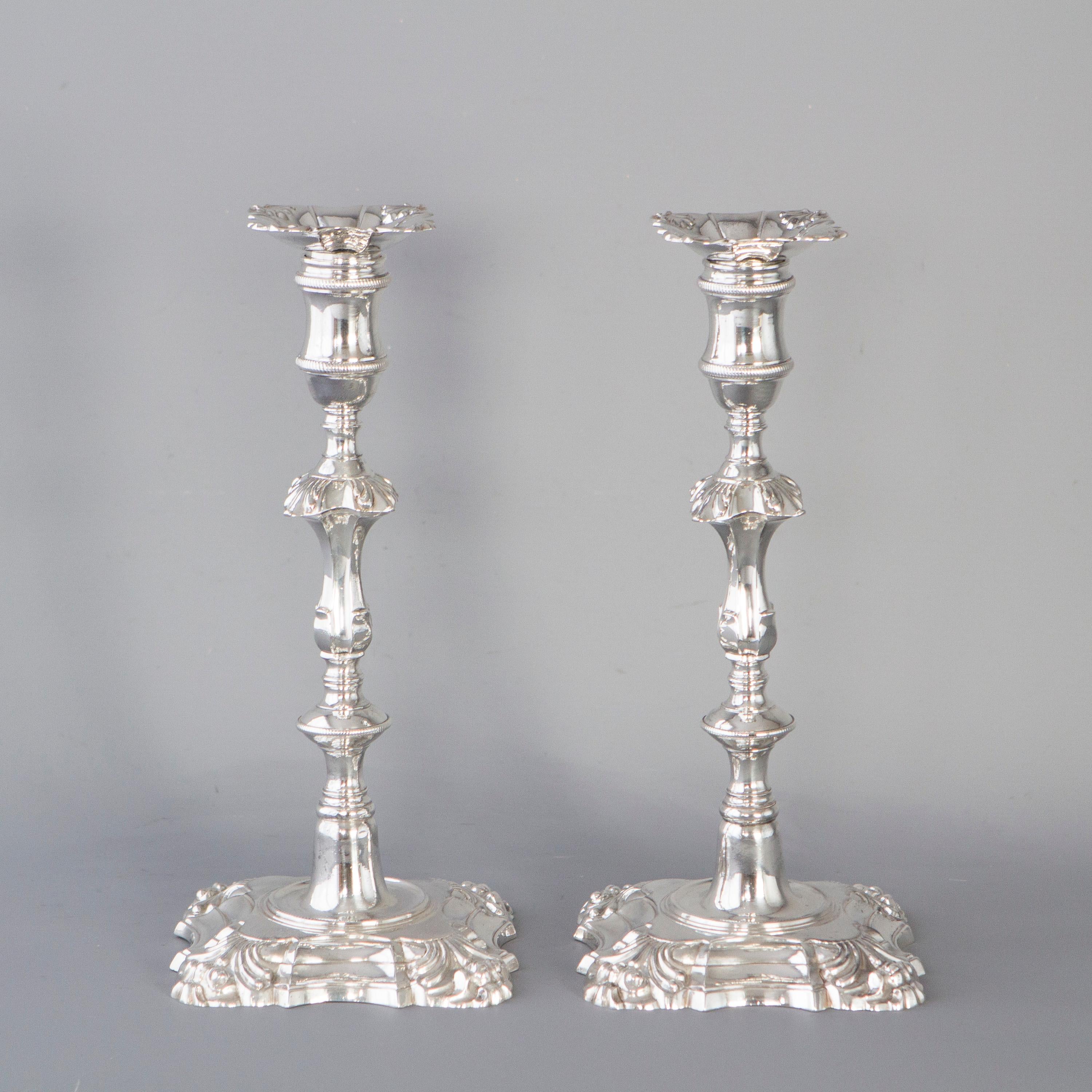 A superb pair of cast George III silver candlesticks by William Cafe, London, 1762. With square bases shaped and stepped with floral form corners. The fluted columns rising above a rope decorated circular knop to a square knop with matching floral