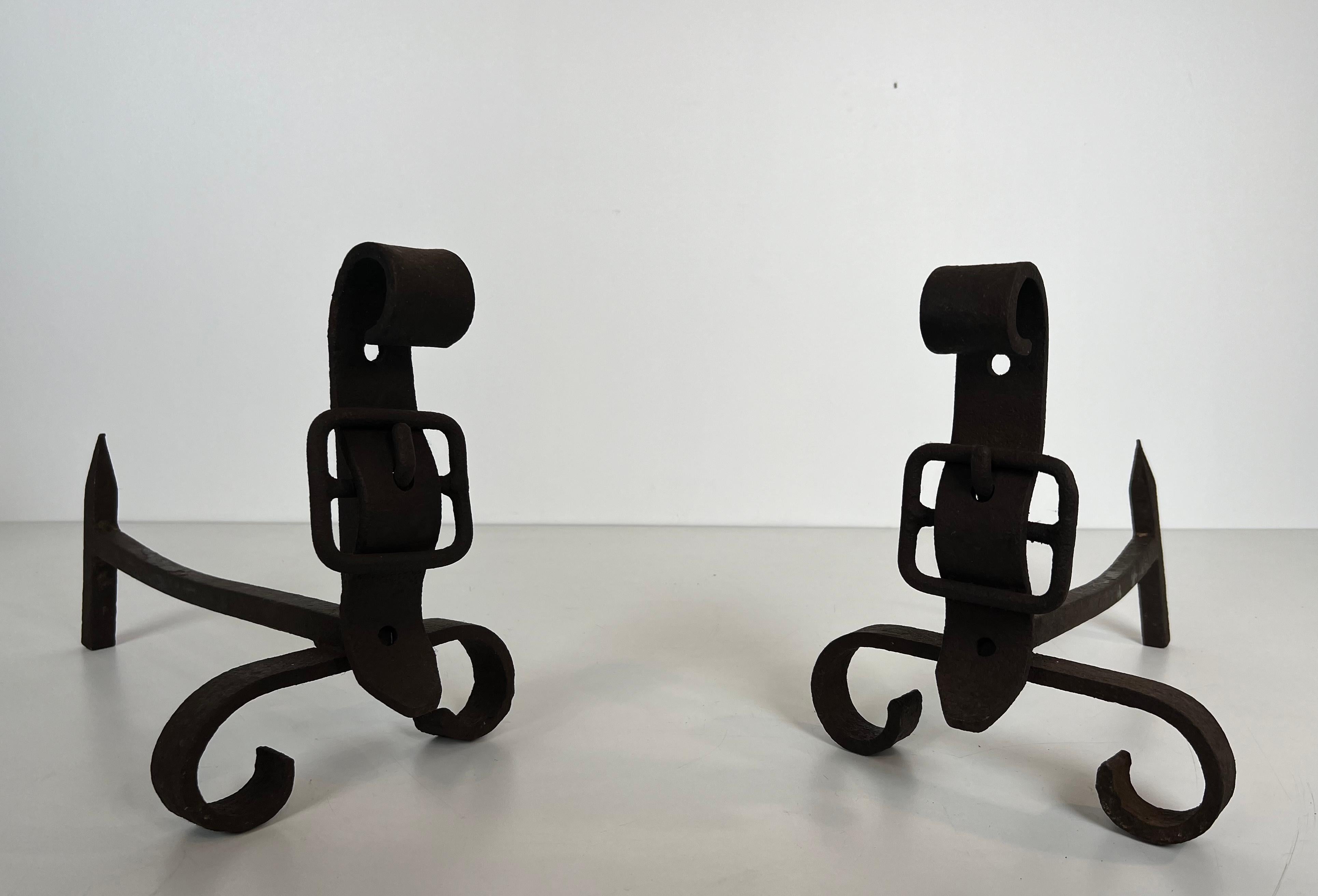 This pair of andirons representing a belt is made of cast iron and wrought iron. This is a French work. Circa 1950.
